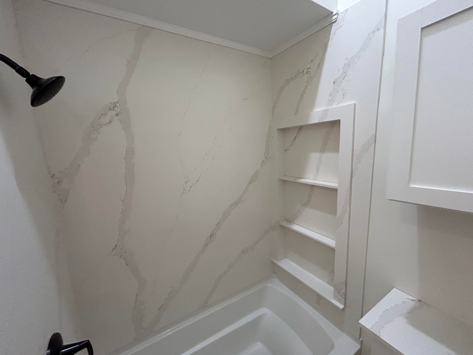 A bathroom with a tub , shower , and shelves.