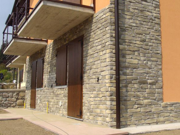a stone building with a balcony and wooden shutters on the windows .