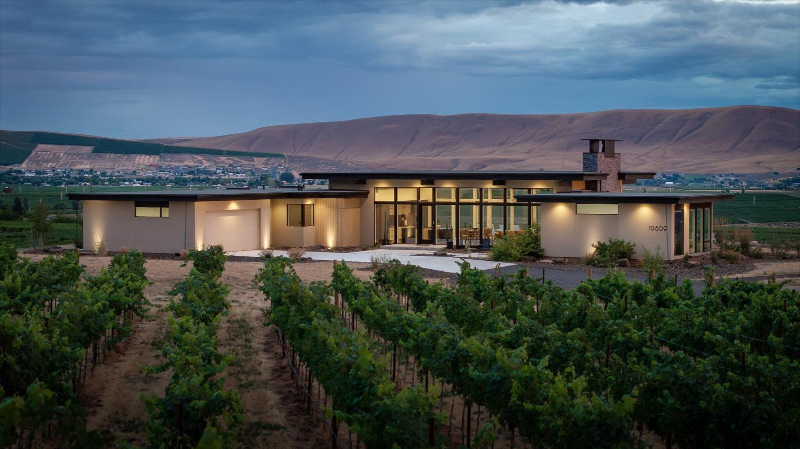 A modern house with two garages and a driveway at sunset.