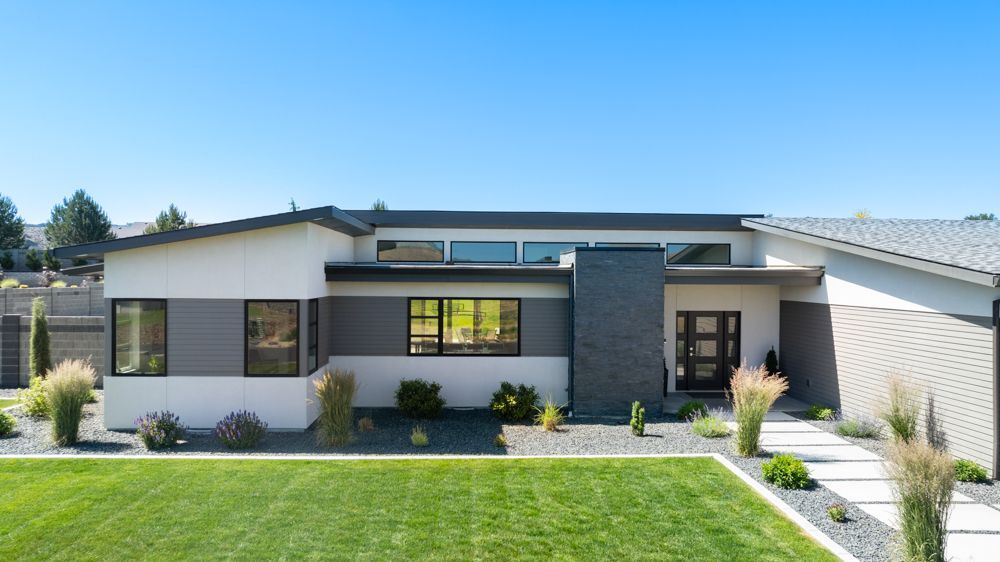 A modern house with a large lawn in front of it.