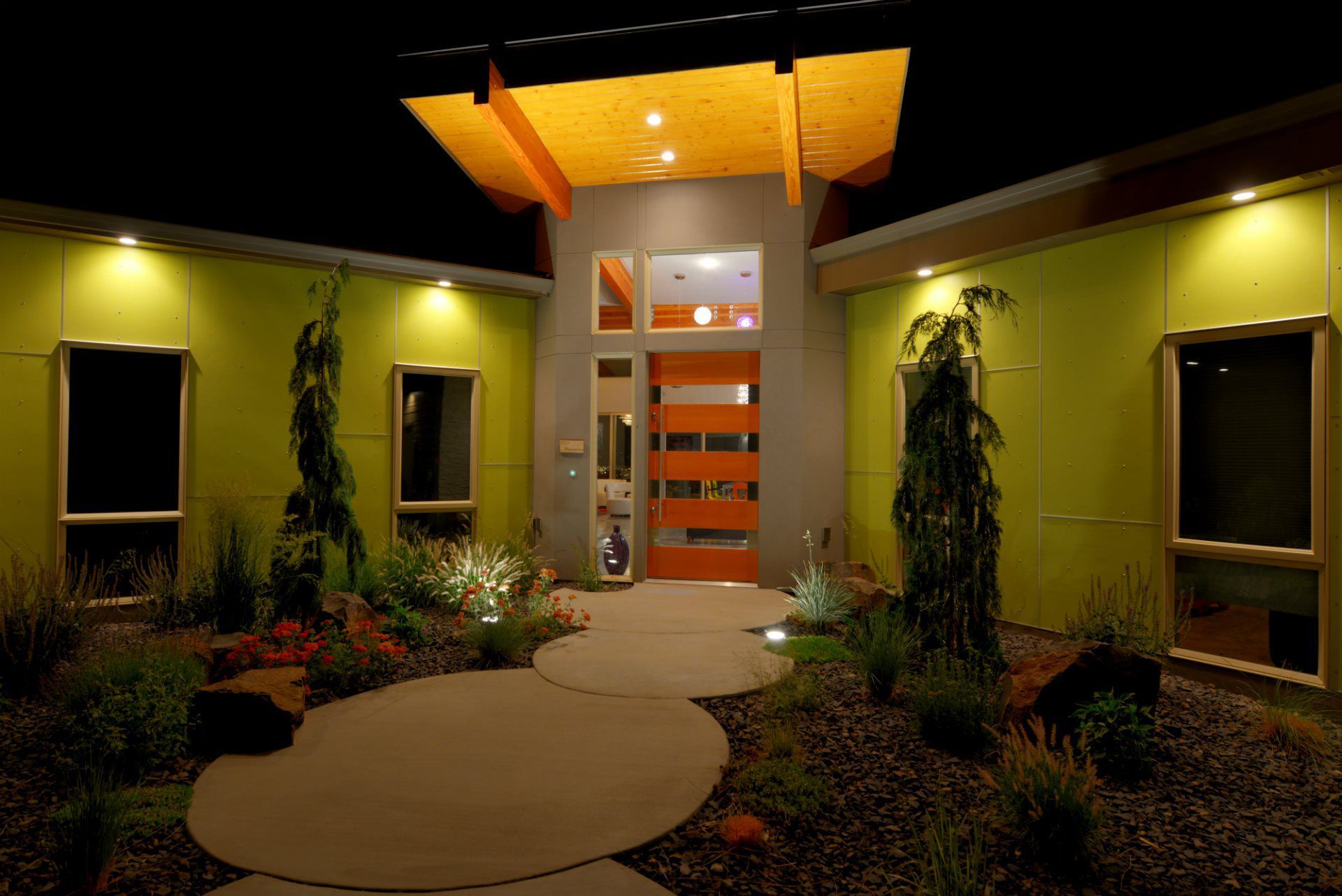 A green house with an orange door is lit up at night