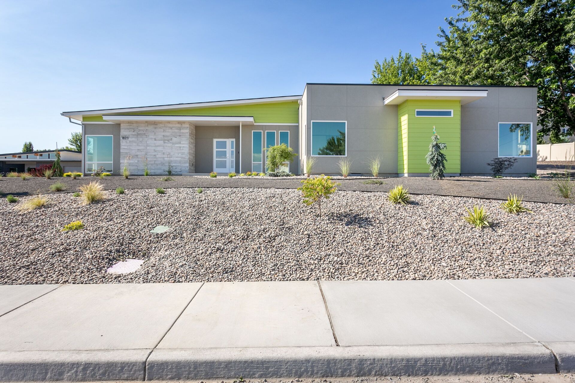 A house with a lot of windows and gravel in front of it