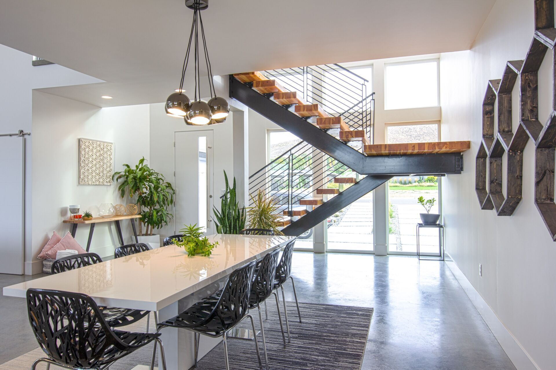 A dining room with a long table and chairs and a staircase.