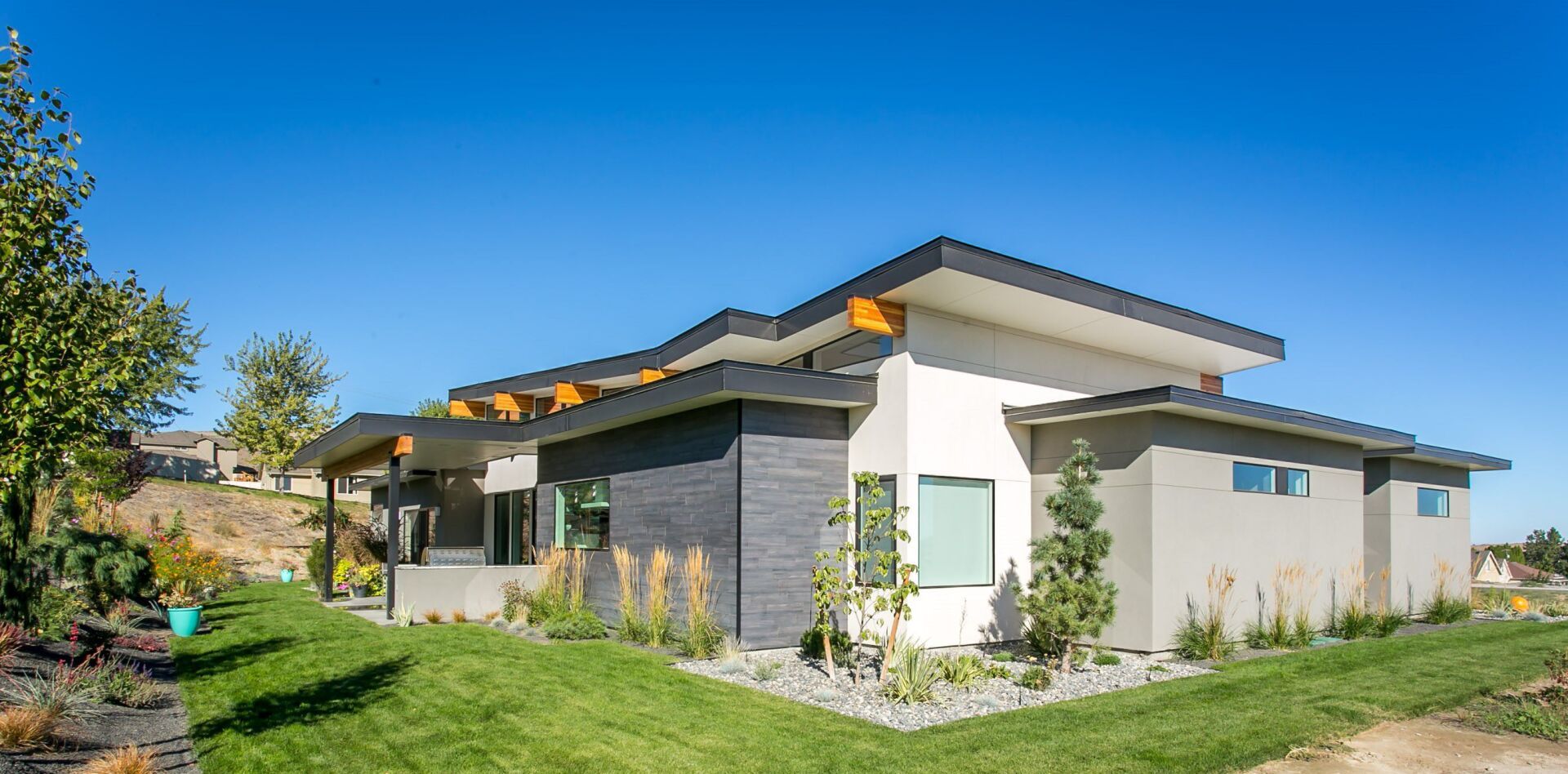 A modern house is sitting on top of a lush green hillside.