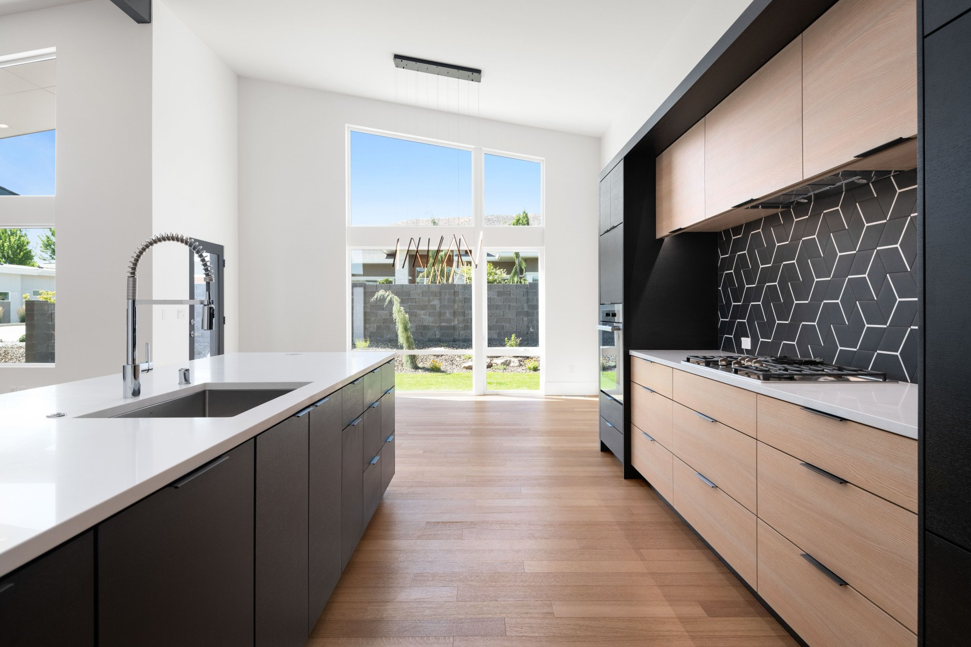 A kitchen with a sink , stove , and large window.