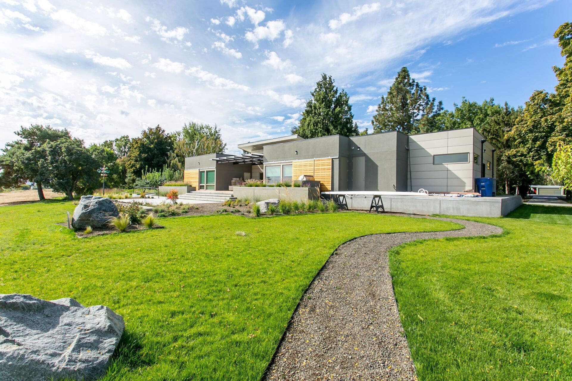 There is a path leading to a large house in the middle of a lush green field.