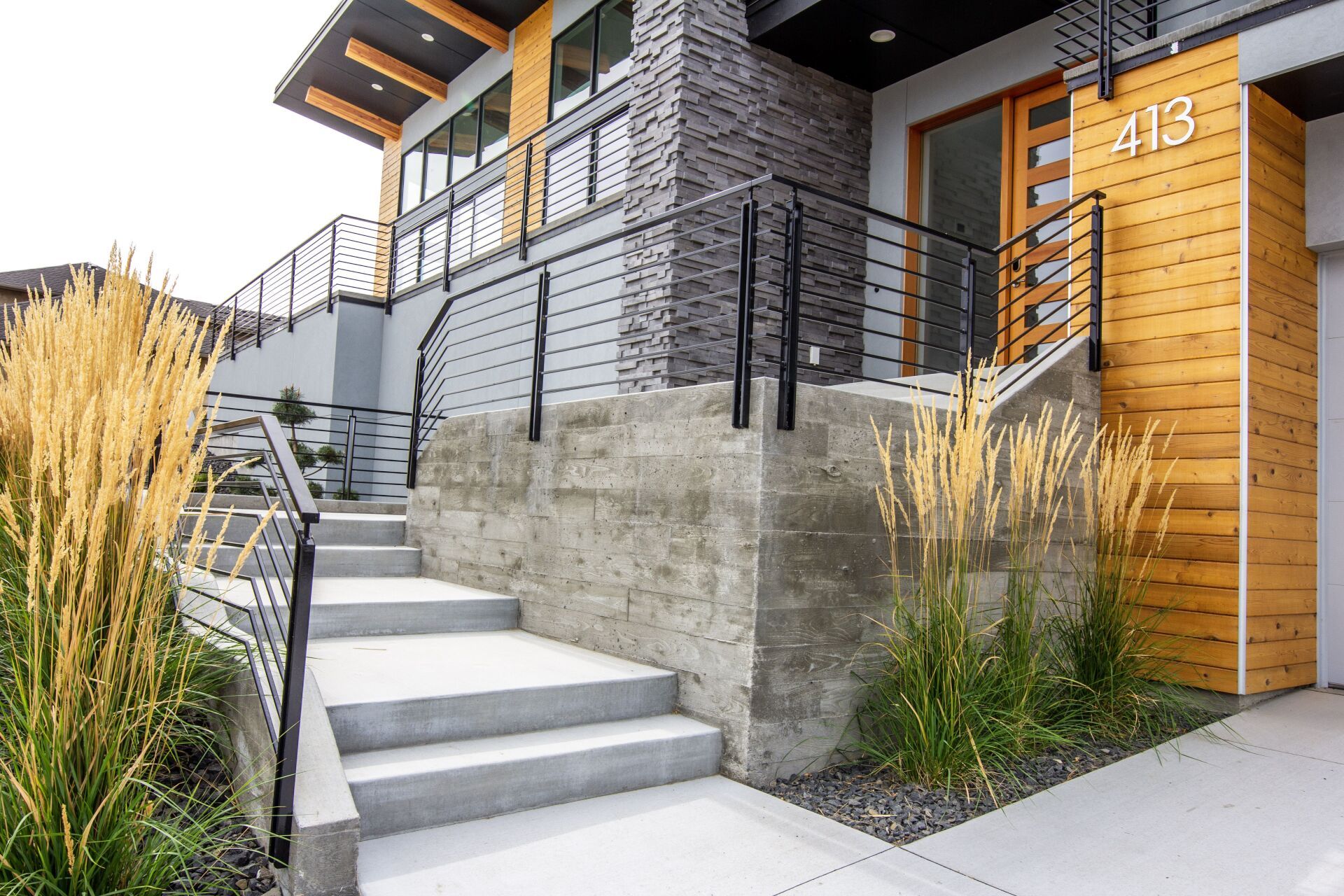 A modern house with stairs leading up to the front door.