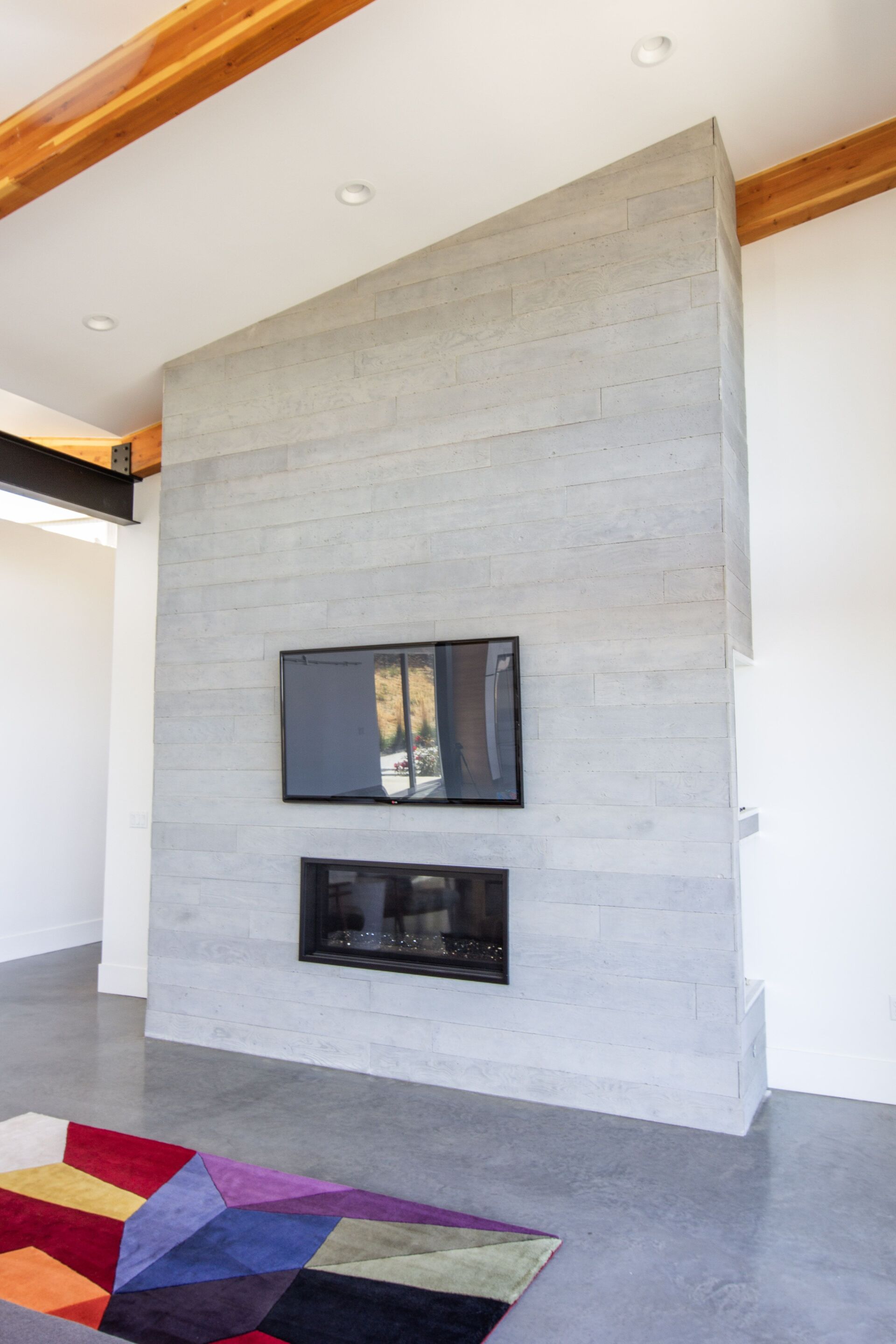 A living room with a fireplace and a flat screen tv on the wall.