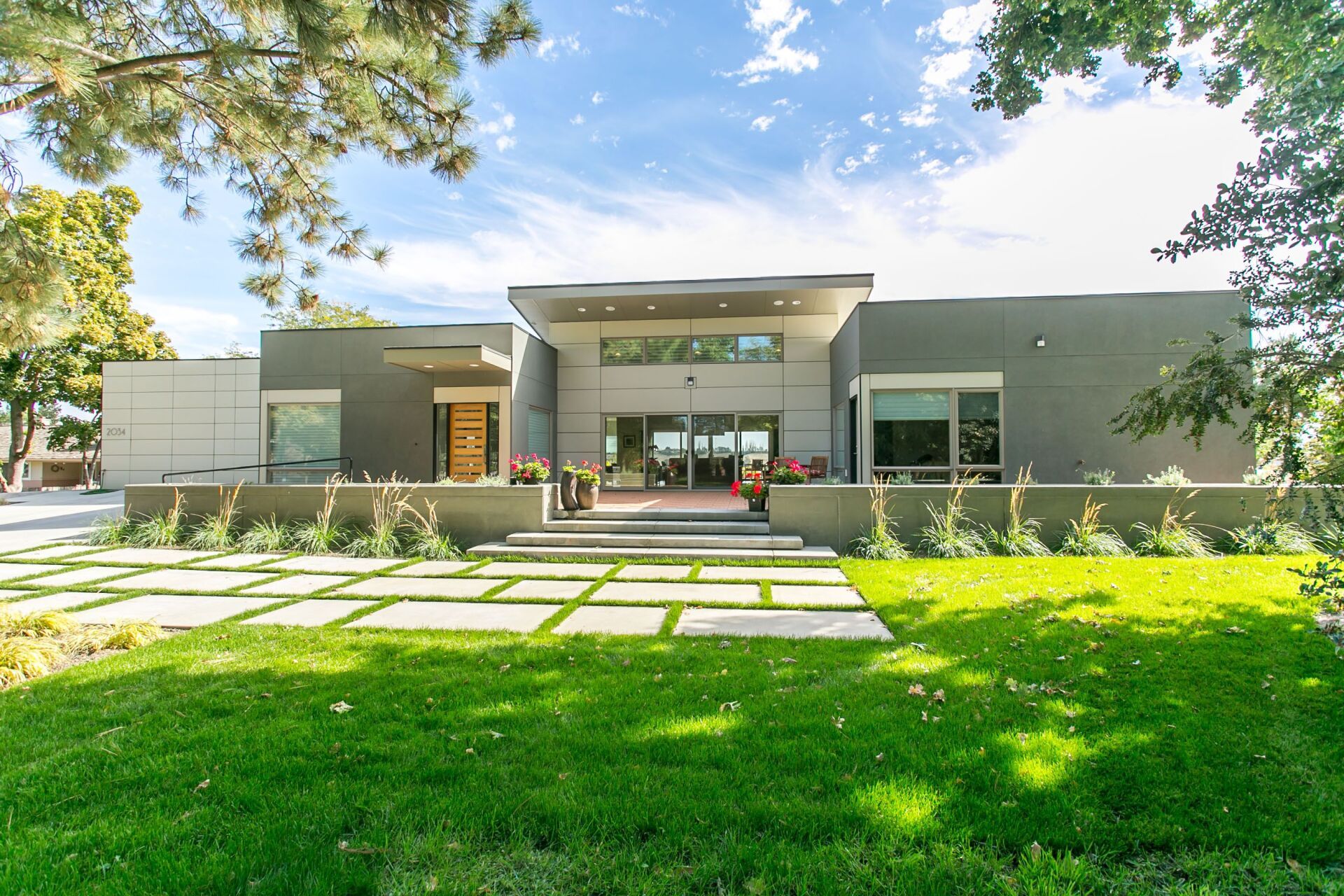 A large modern house with a lush green lawn in front of it.