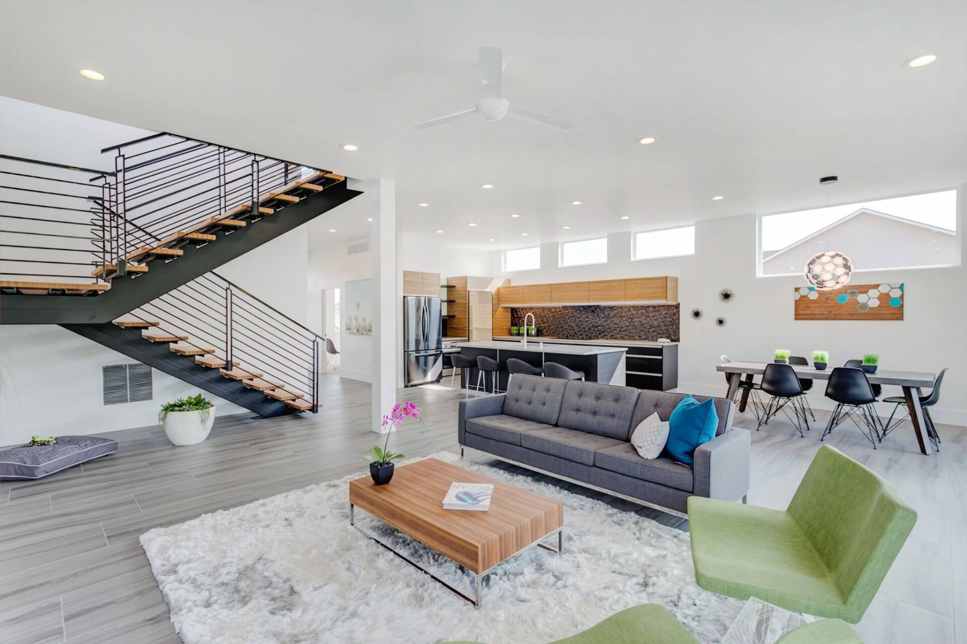 A living room with a couch , coffee table , chairs and stairs.