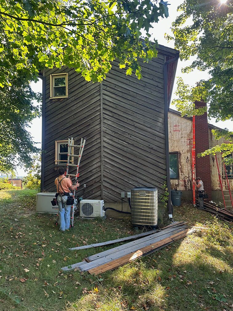 A man is standing in front of a house with a ladder.