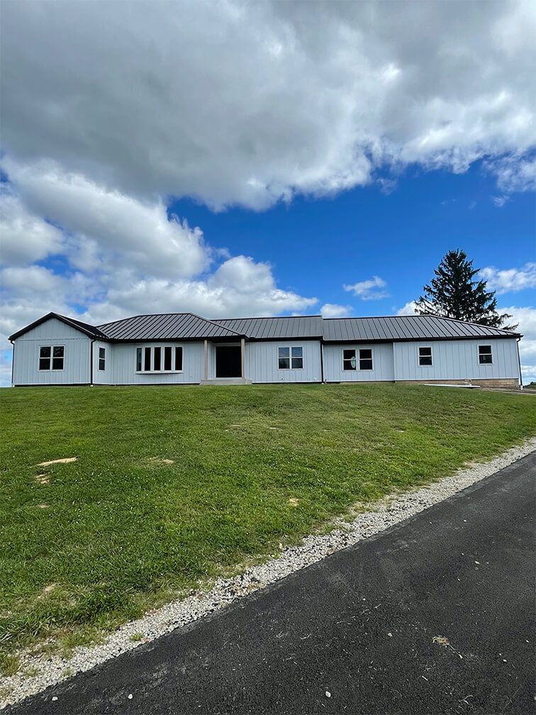 A large white house is sitting on top of a lush green hill.