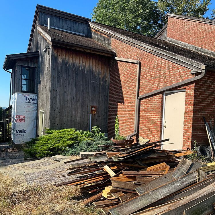 A pile of wood is in front of a brick building