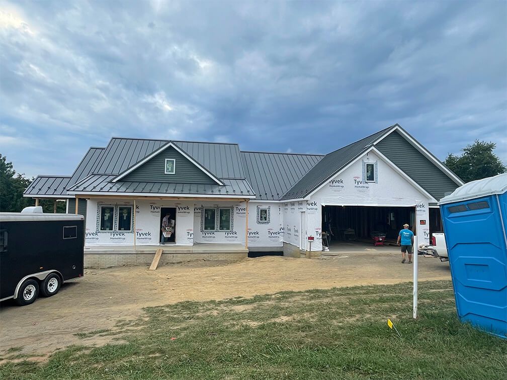 A man is standing in front of a house under construction.