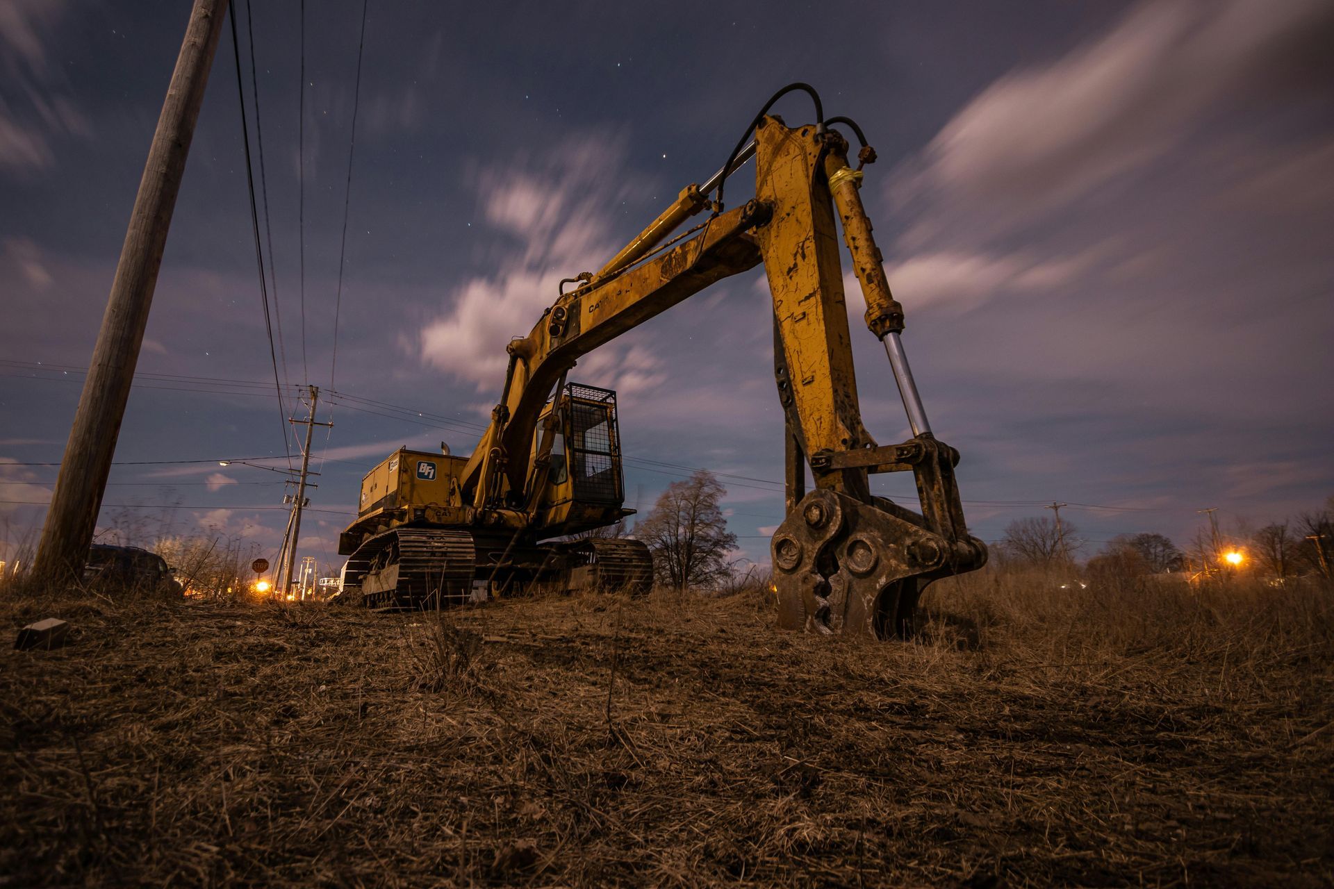 A yellow excavator is parked in a field at night.