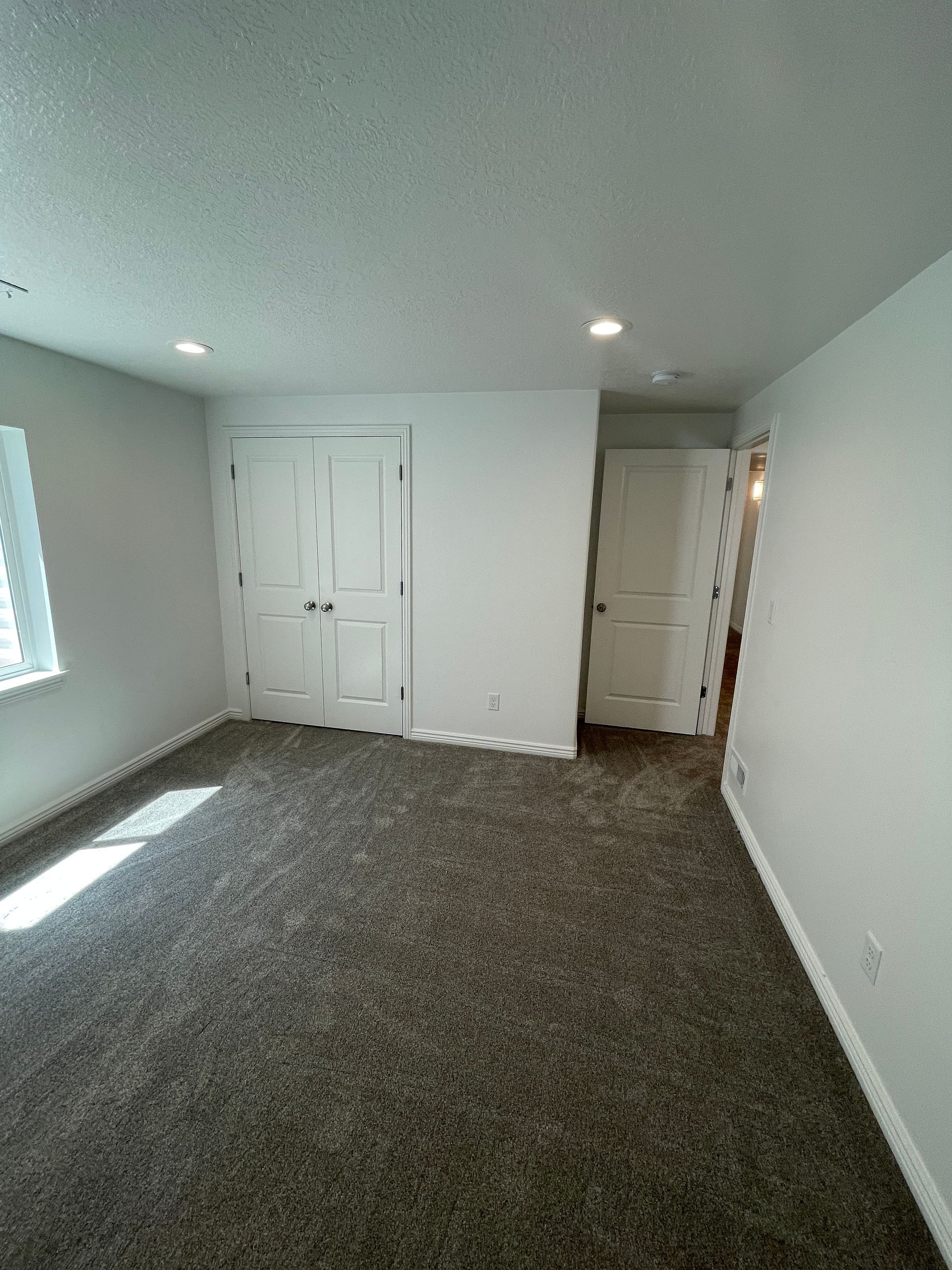 A large empty room with a carpeted floor and white walls.