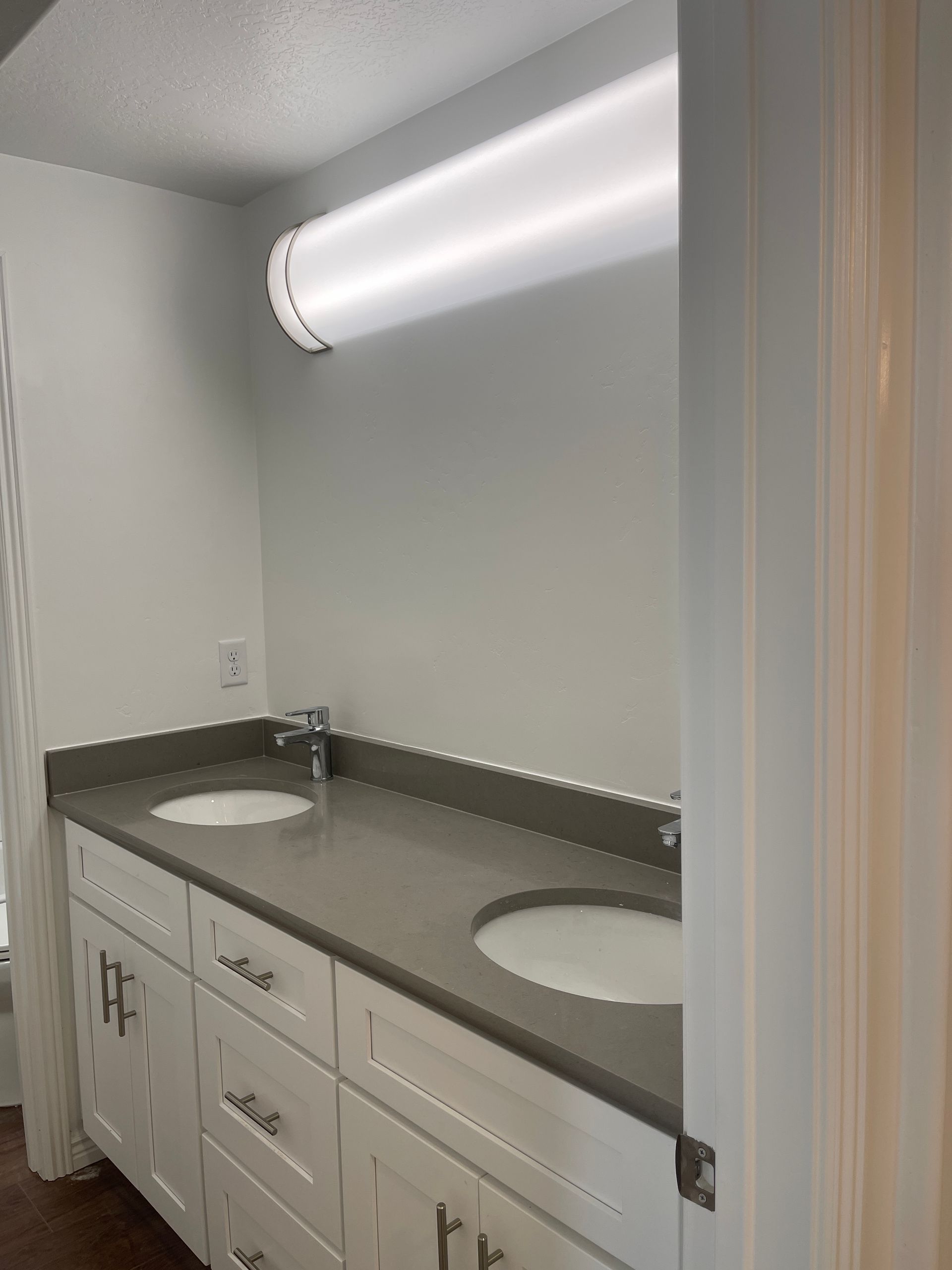 A bathroom with two sinks and a light on the wall.