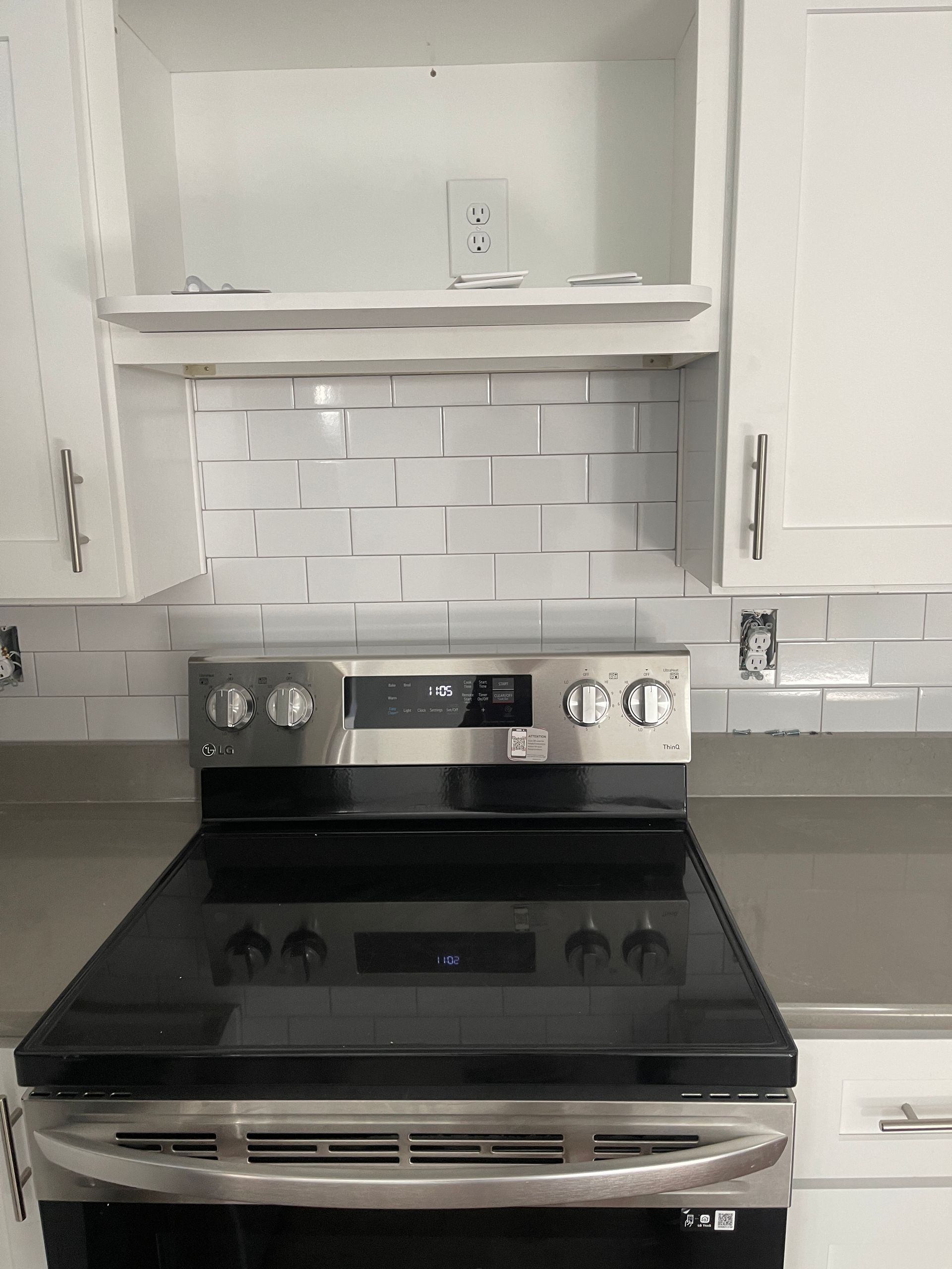 A black stove top oven is in a kitchen with white cabinets.