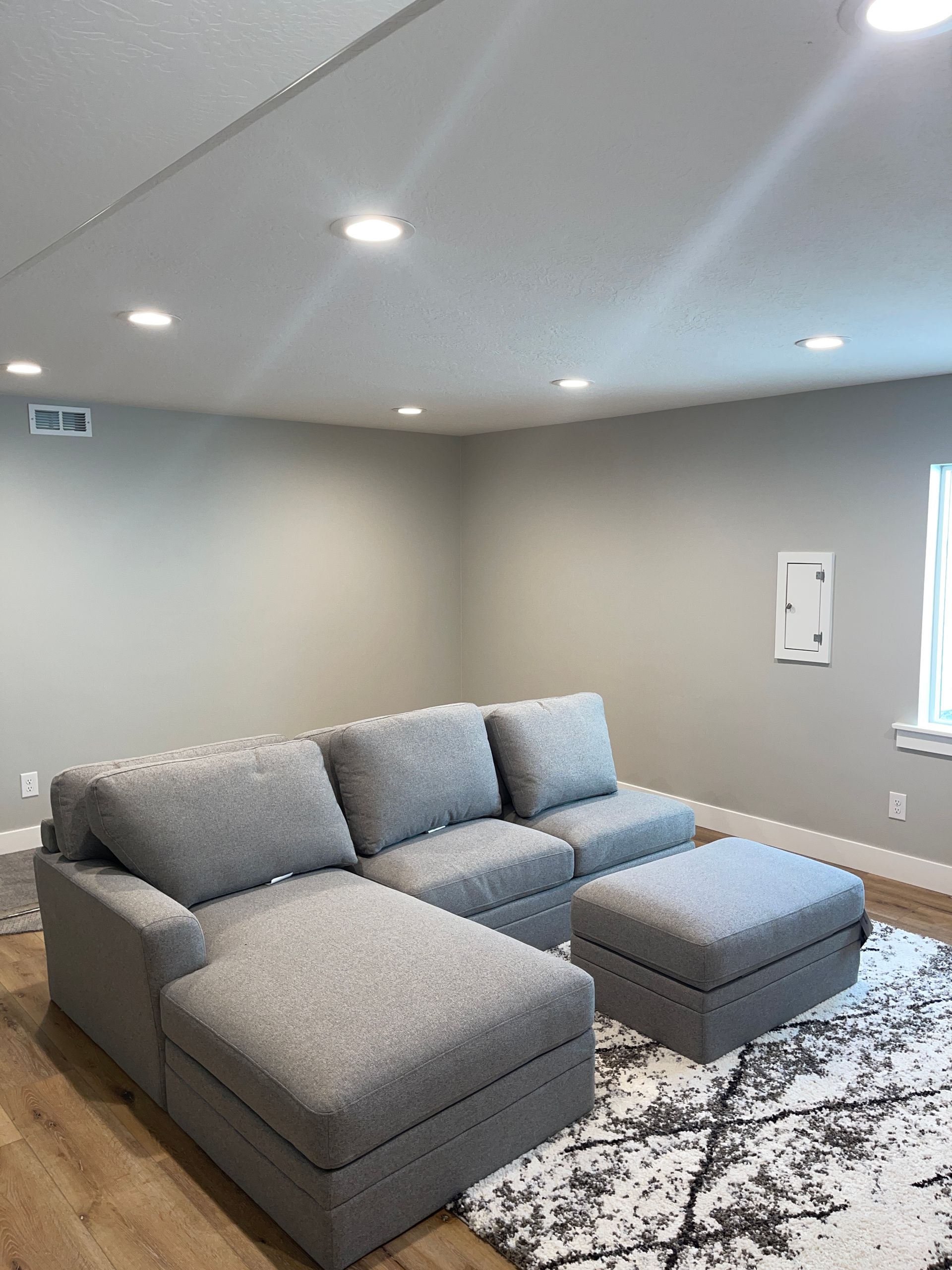 A living room with a couch , ottoman , and rug.
