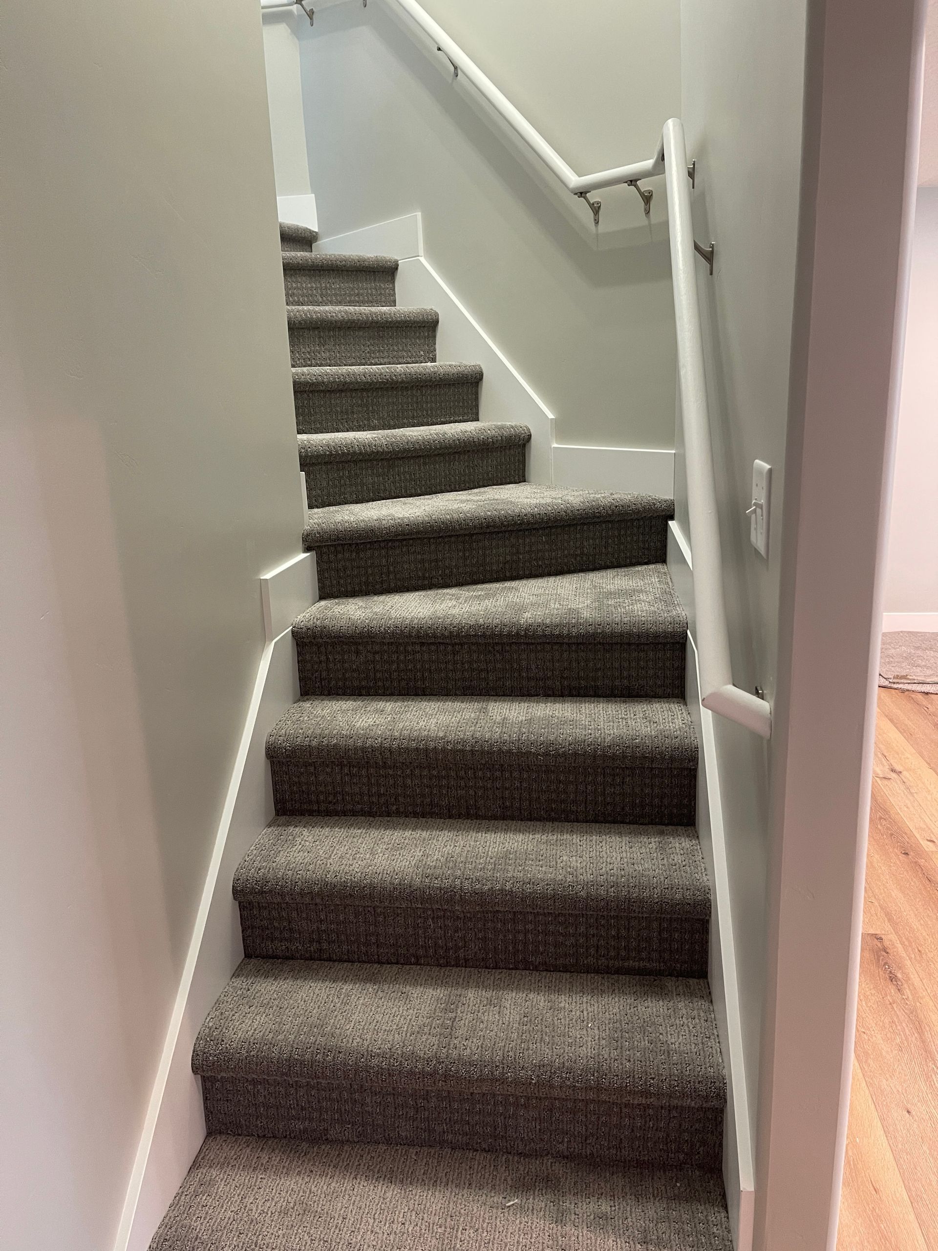 A set of stairs with carpeted steps and a white railing.