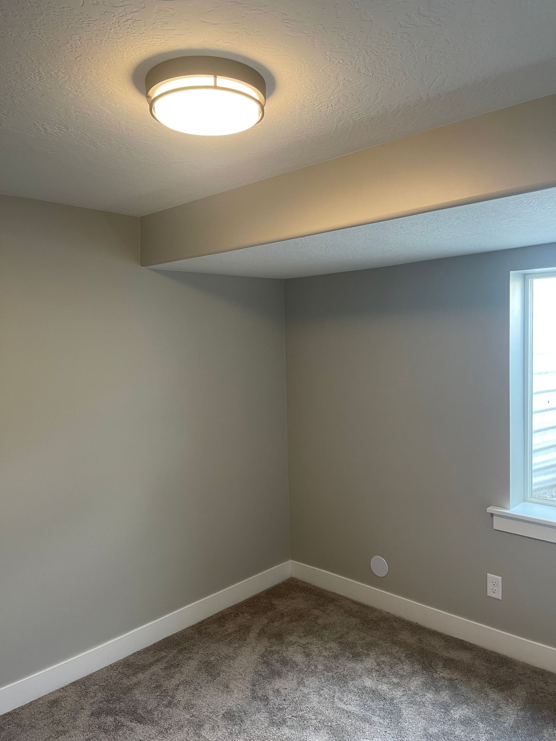 An empty room with a ceiling light and a window.