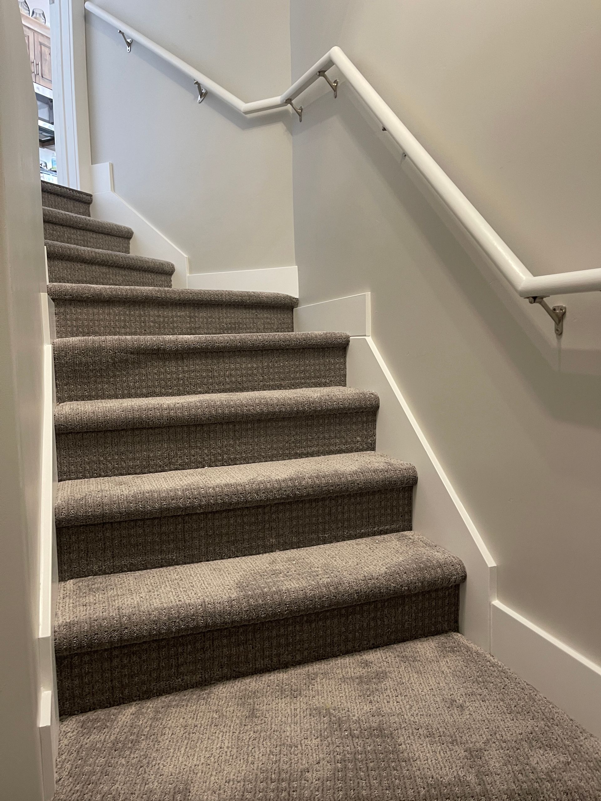 A set of stairs with carpeted steps and a white railing.