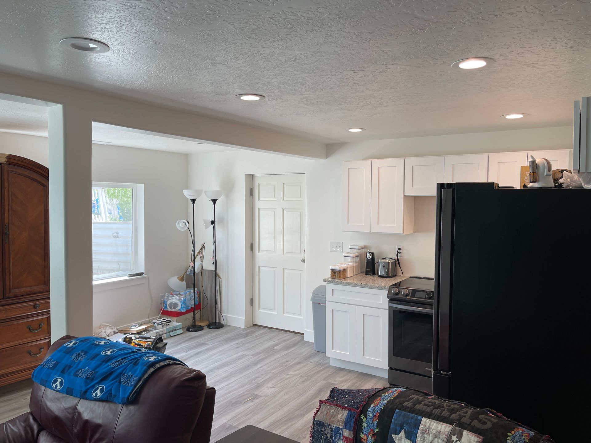 A living room with a black refrigerator and a black stove.