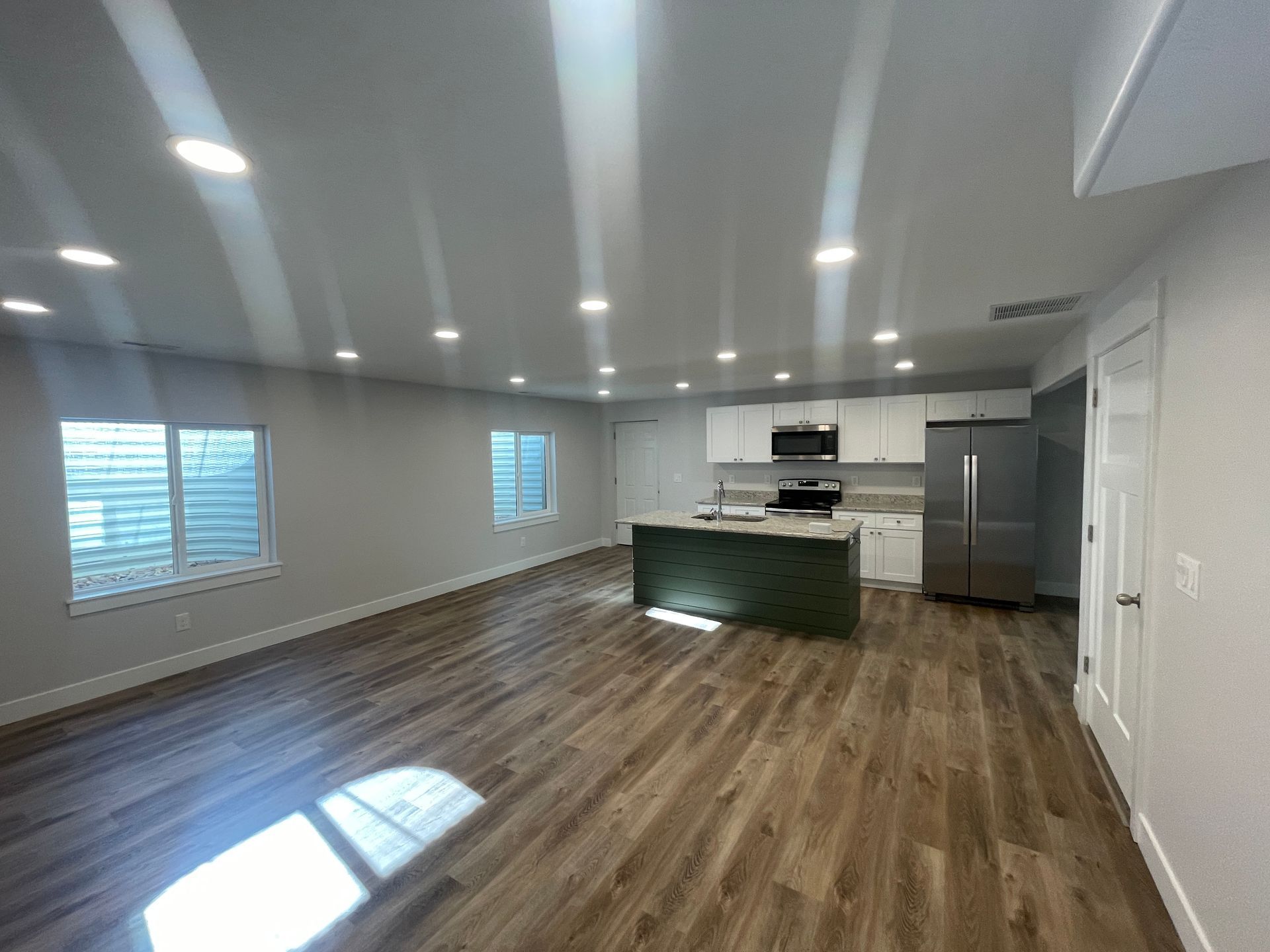 A large living room with hardwood floors and a kitchen.