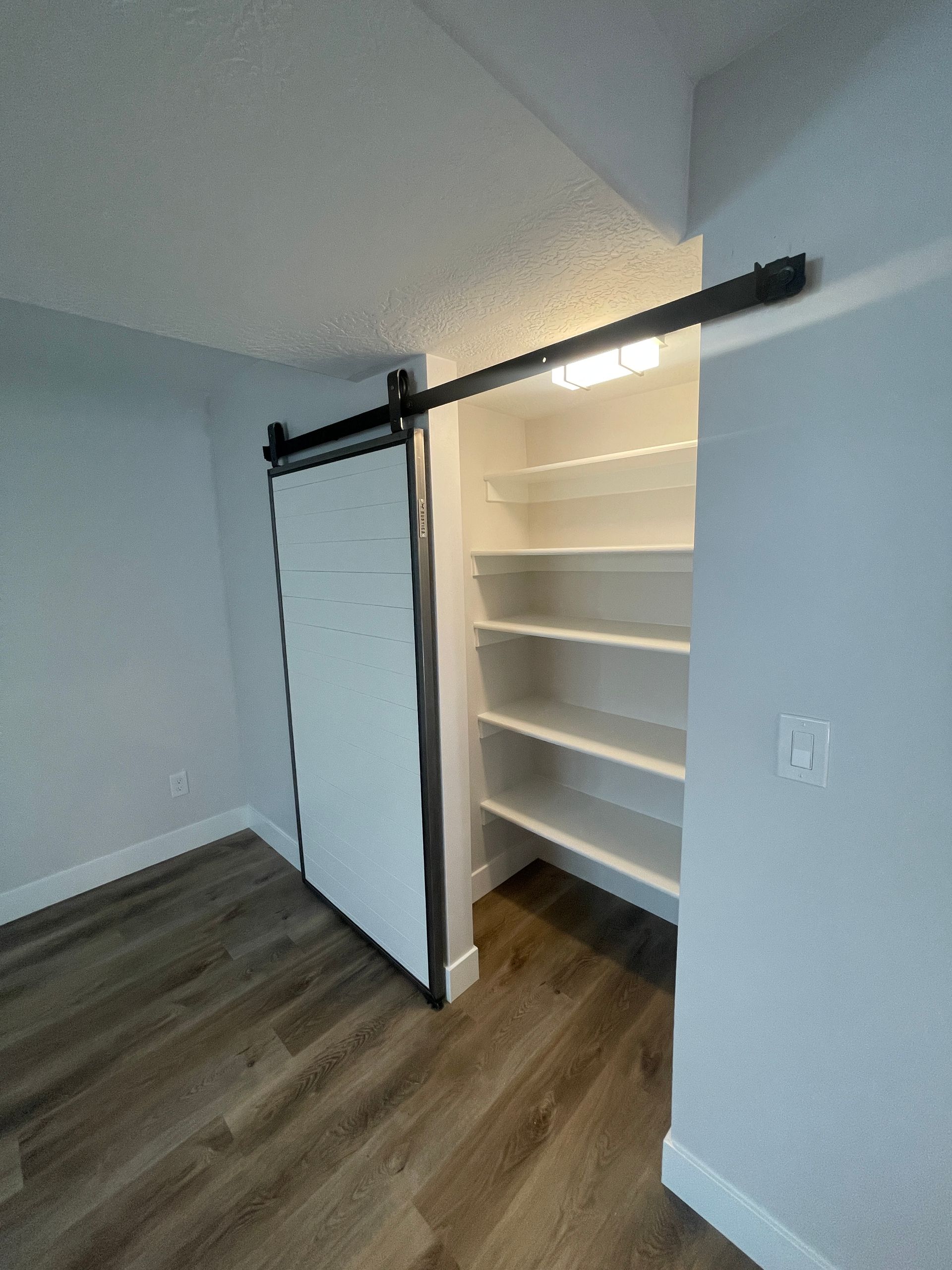 A closet with a sliding barn door and shelves