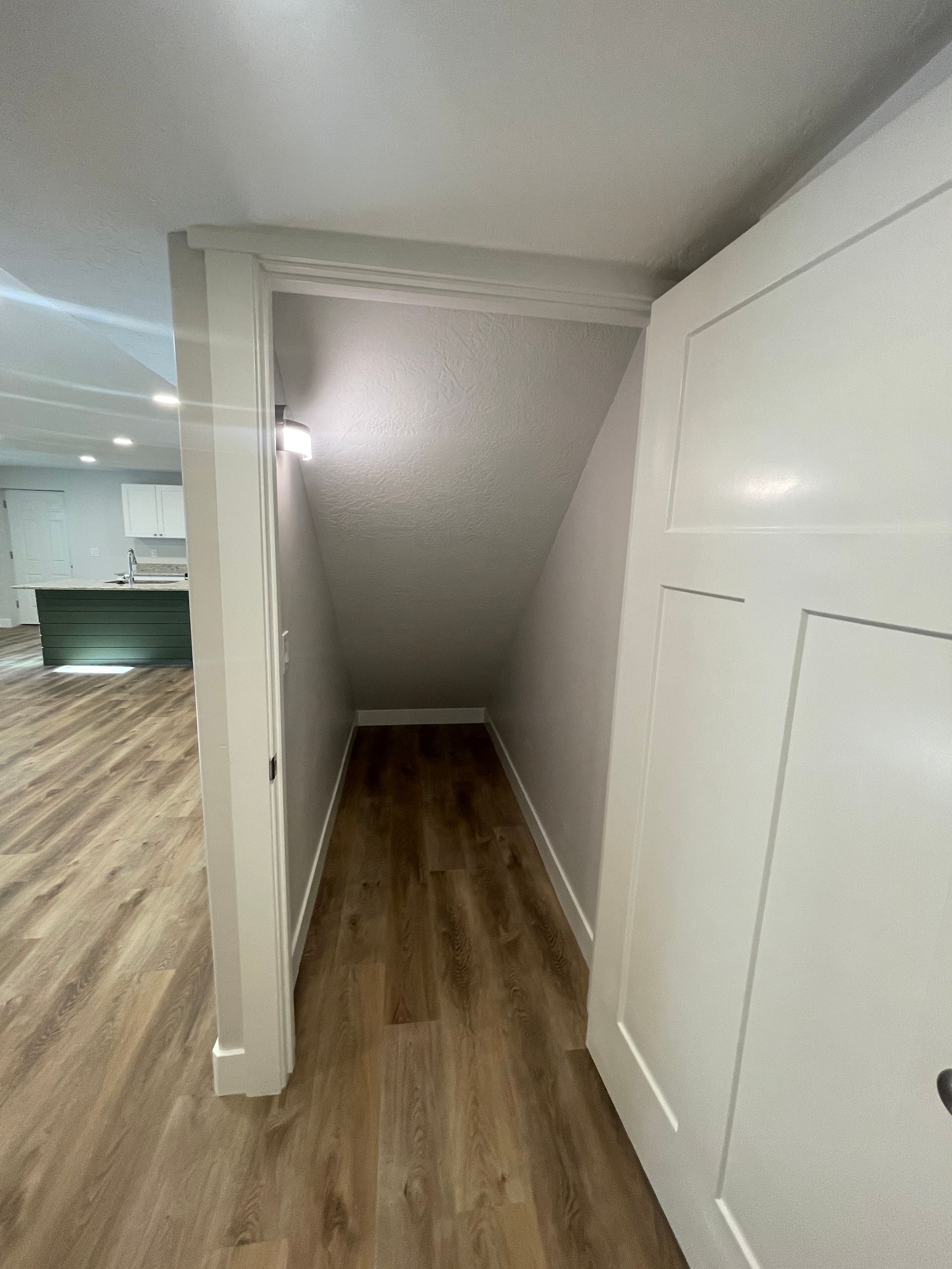 A hallway with hardwood floors and a staircase in the background.