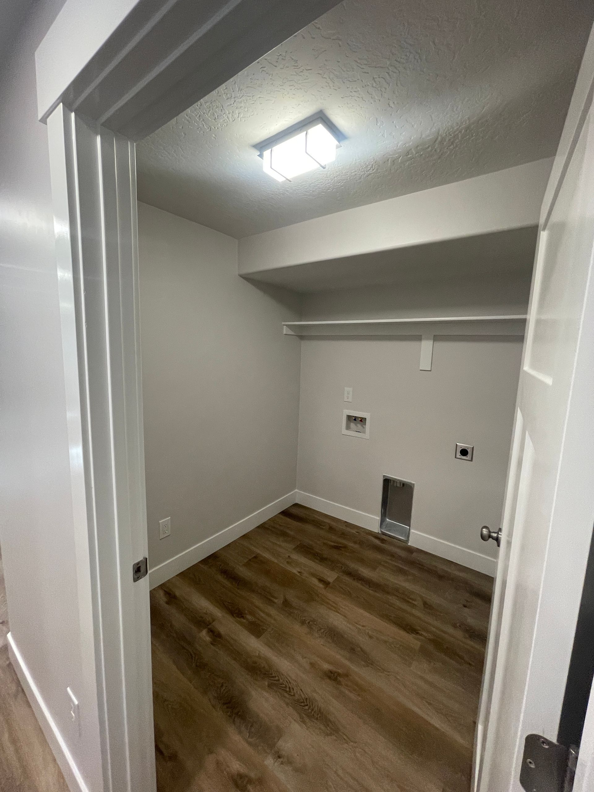 A laundry room with hardwood floors and a door leading to it.