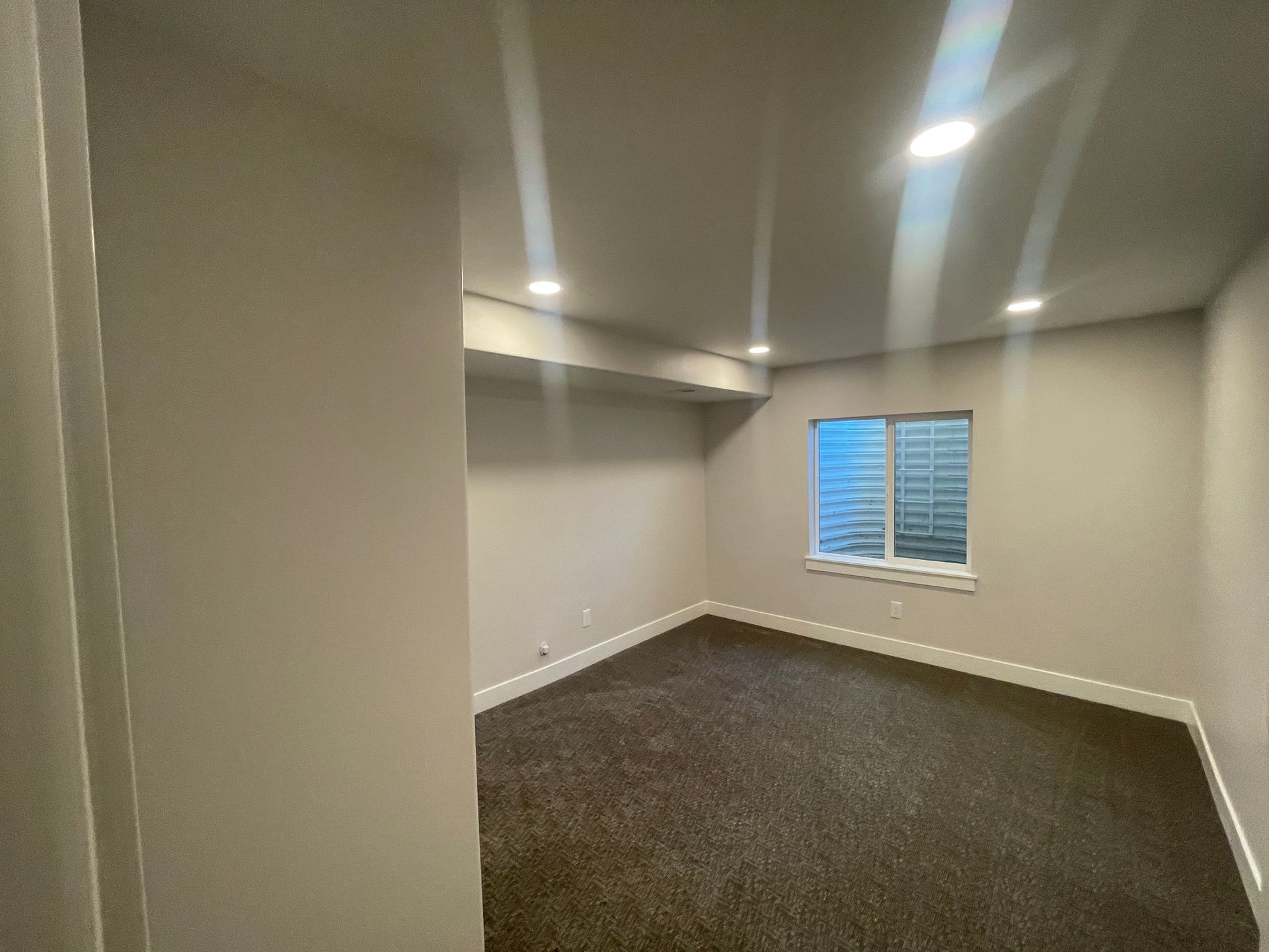 An empty room with a window and a carpeted floor.