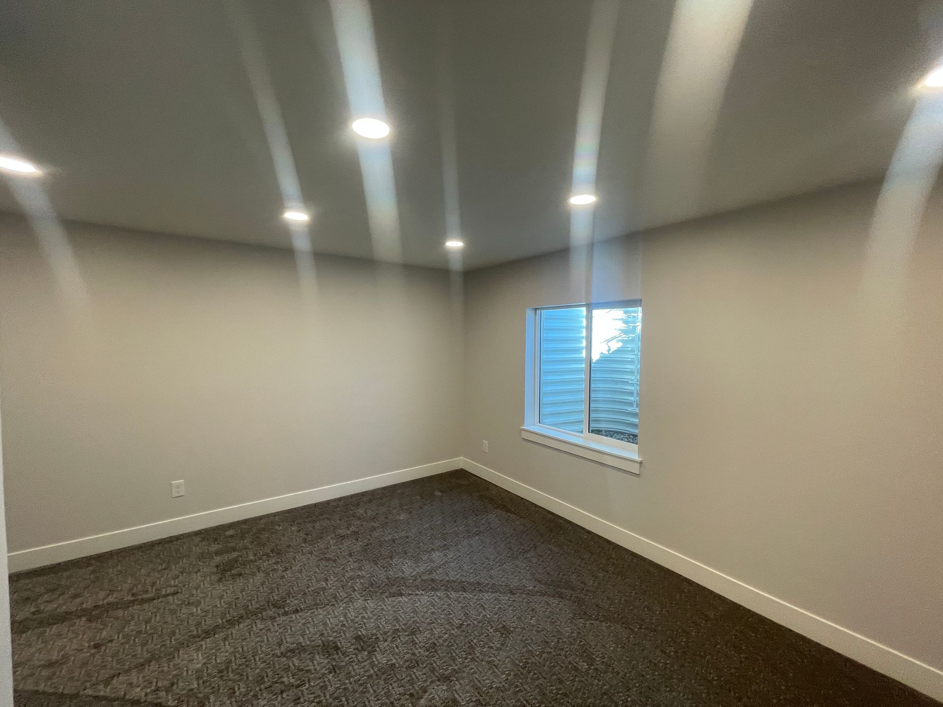 An empty room with a window and a carpeted floor.