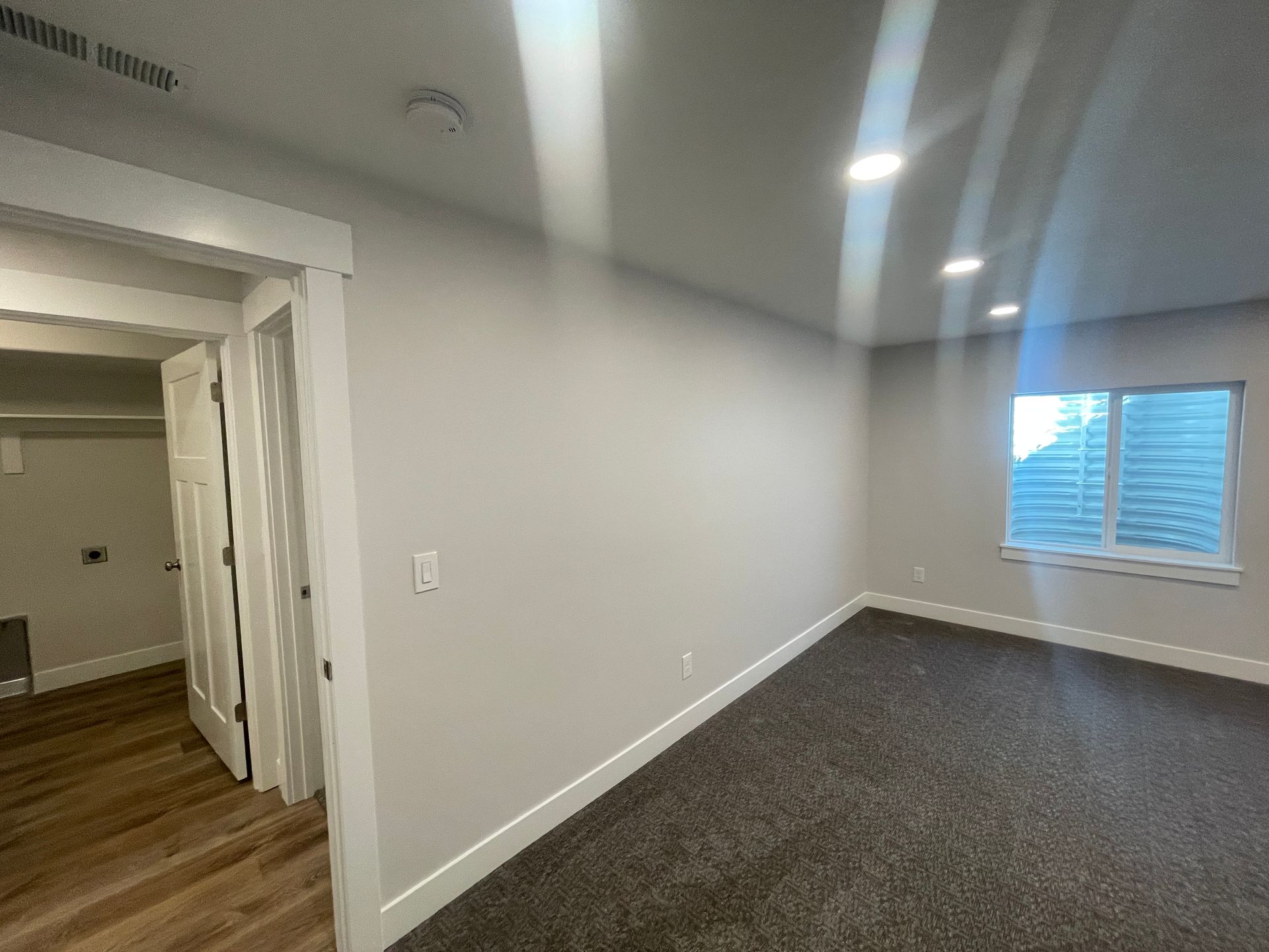 An empty room with a window and a closet in a house.