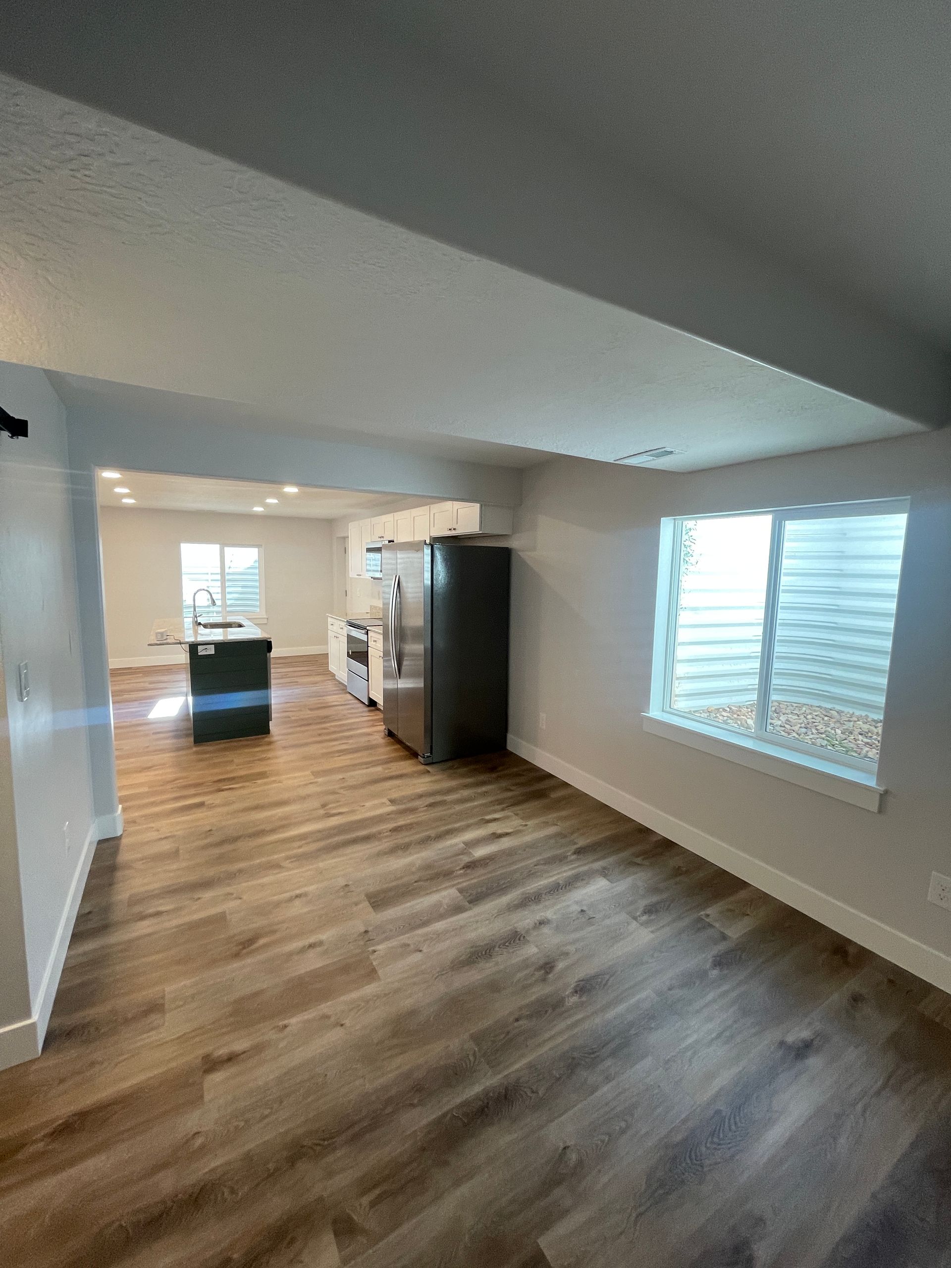 A living room with hardwood floors and a refrigerator in a house.