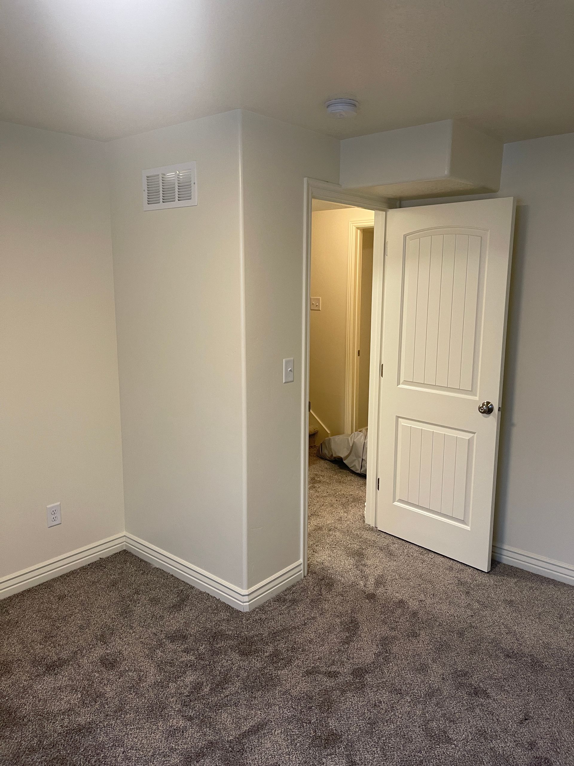 An empty room with a carpeted floor and a door leading to a bathroom.