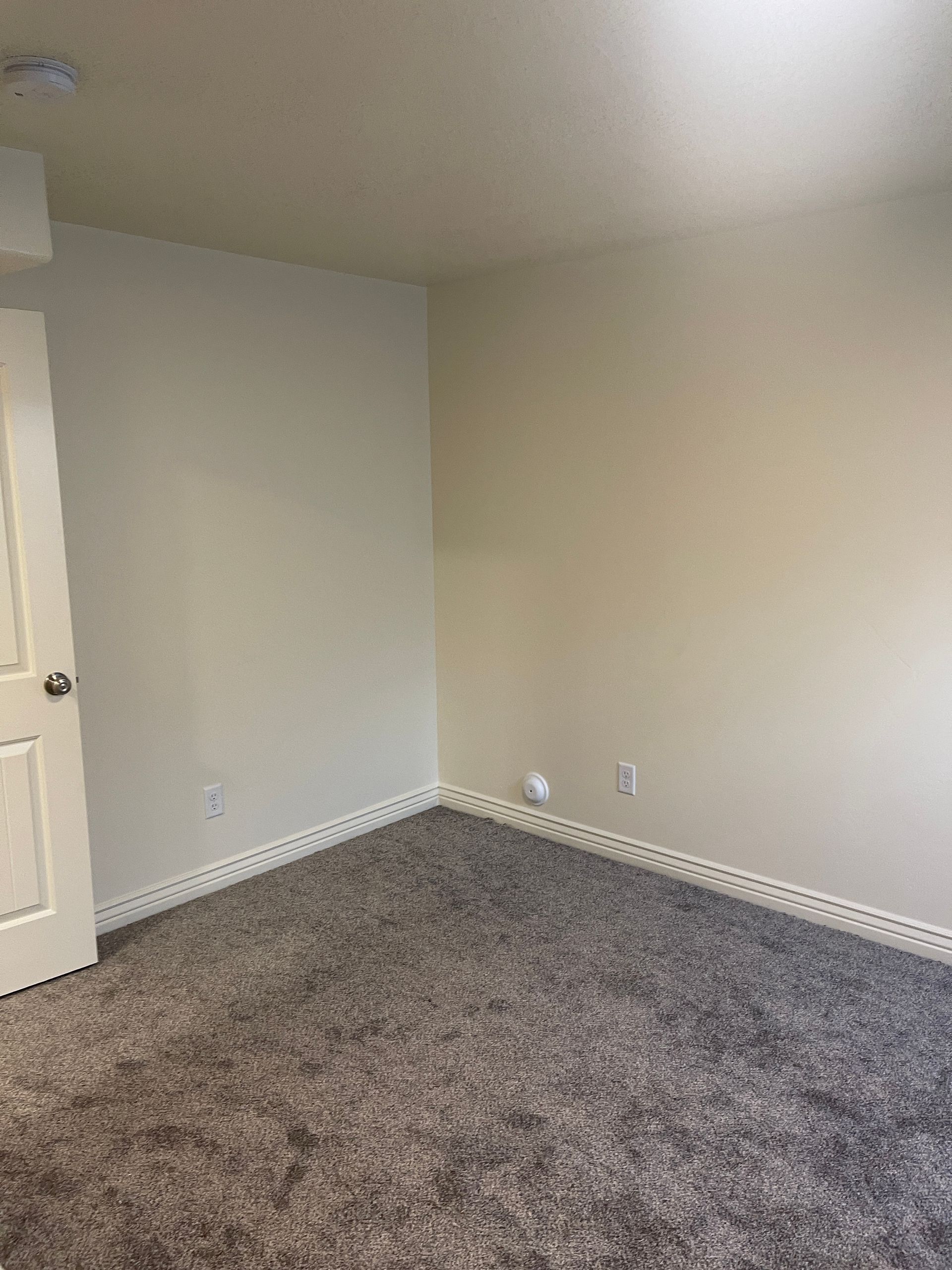 An empty bedroom with a carpeted floor and white walls.