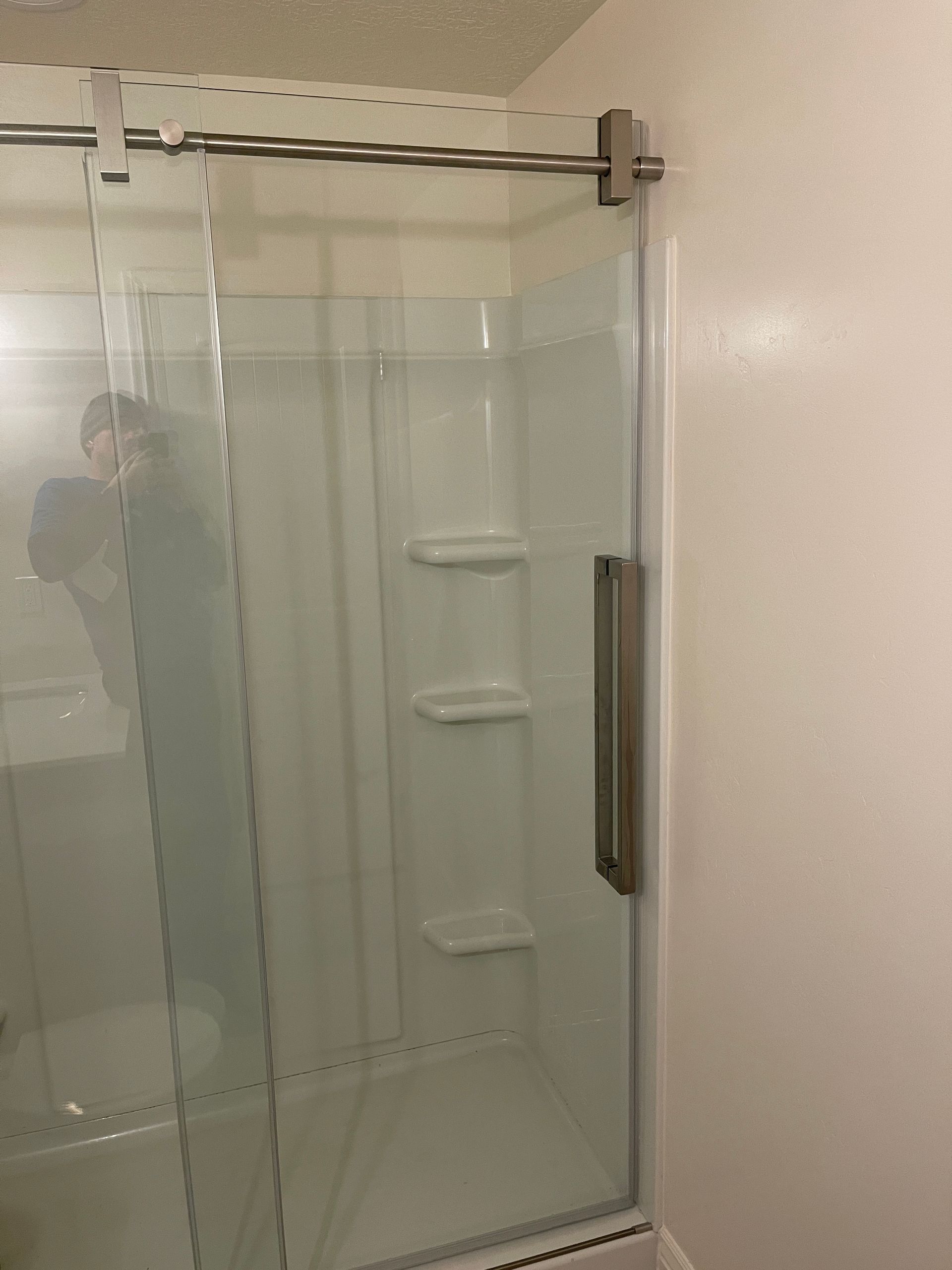 A bathroom with a sliding glass shower door and shelves.