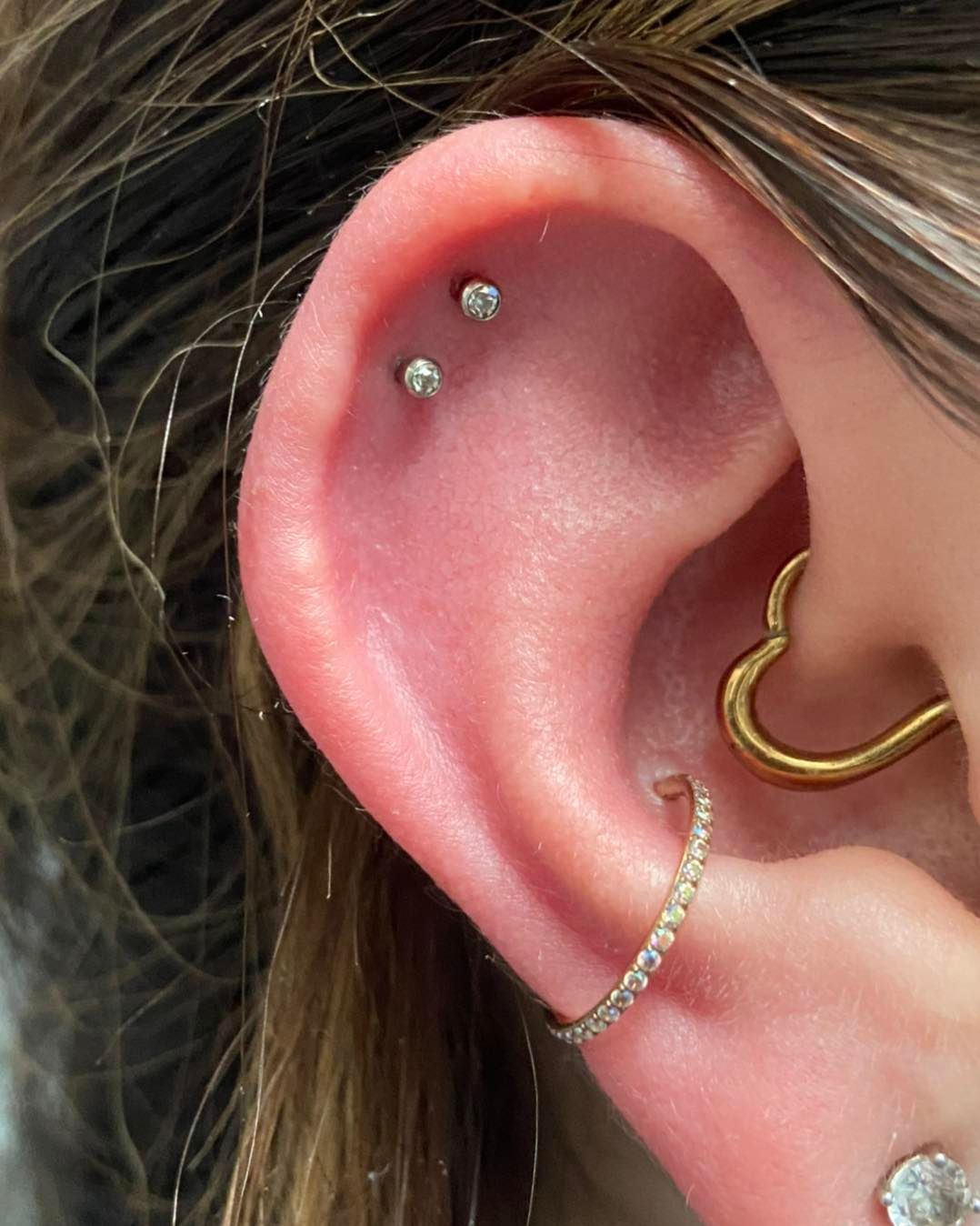 a close up of a woman 's ear with a heart shaped piercing