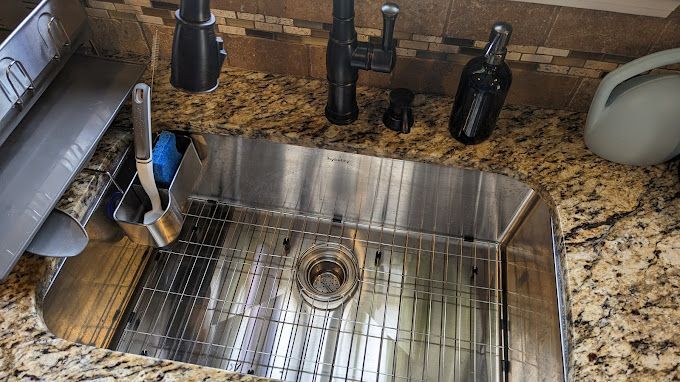 A stainless steel kitchen sink is sitting on top of a granite counter.