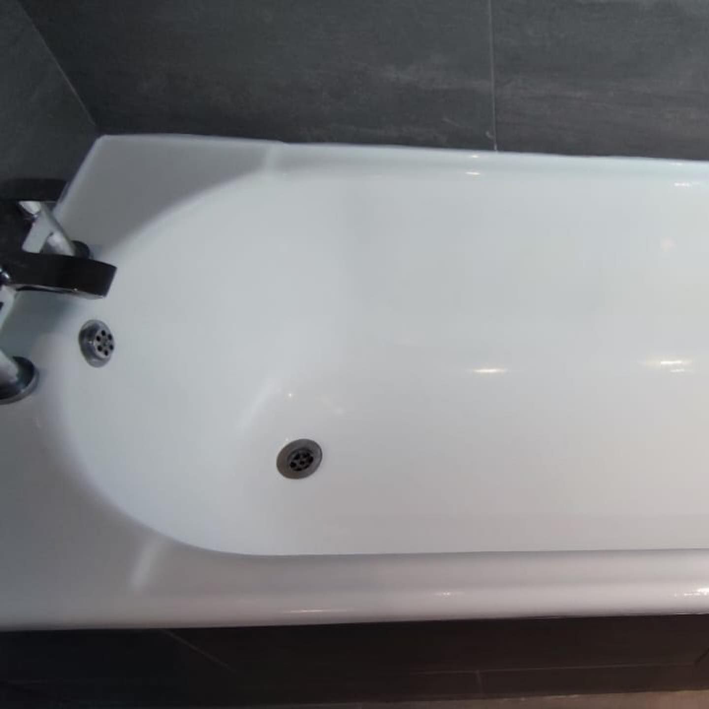 A white bathtub with a black faucet in a bathroom.