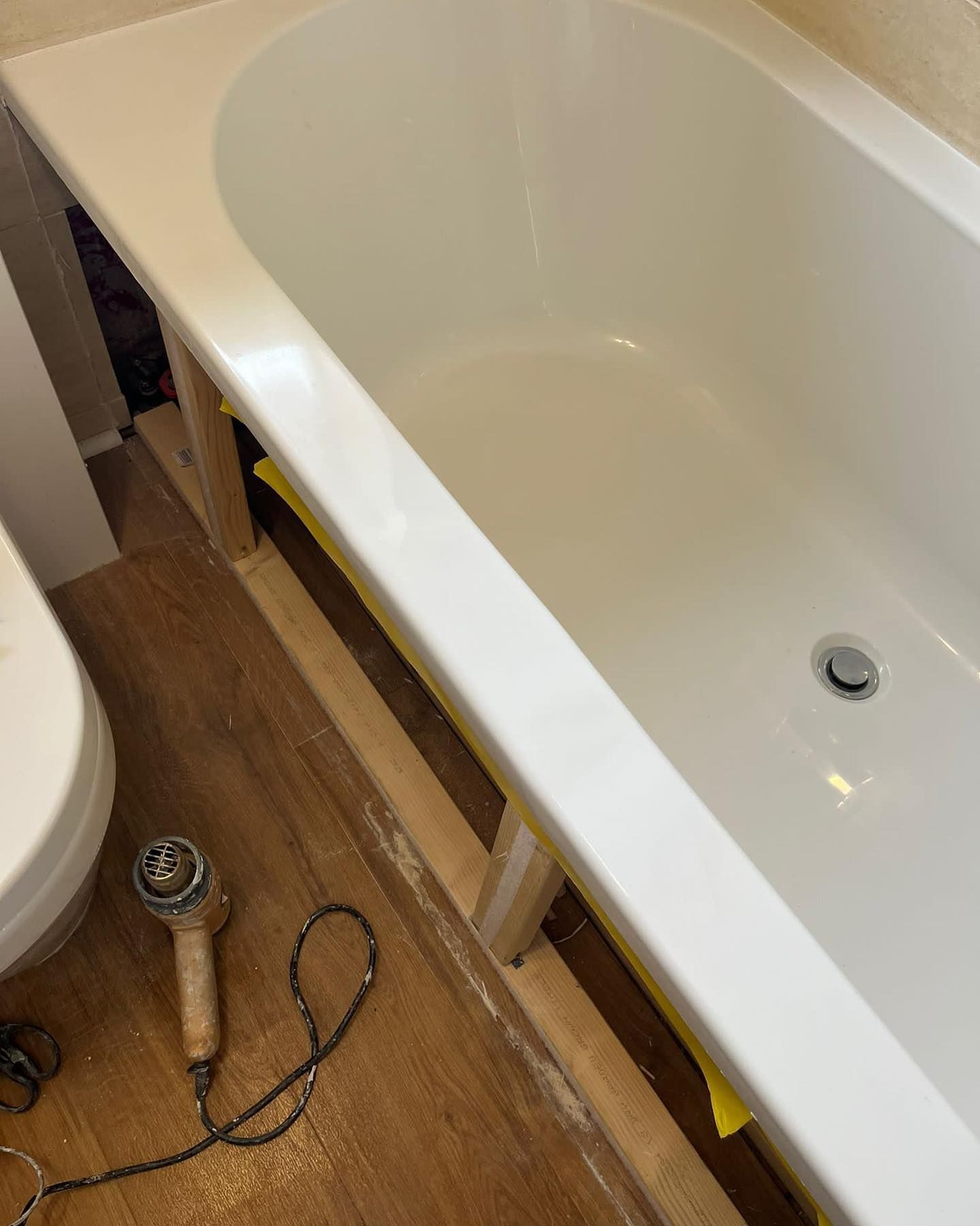 A bathtub in a bathroom next to a toilet and a hair dryer