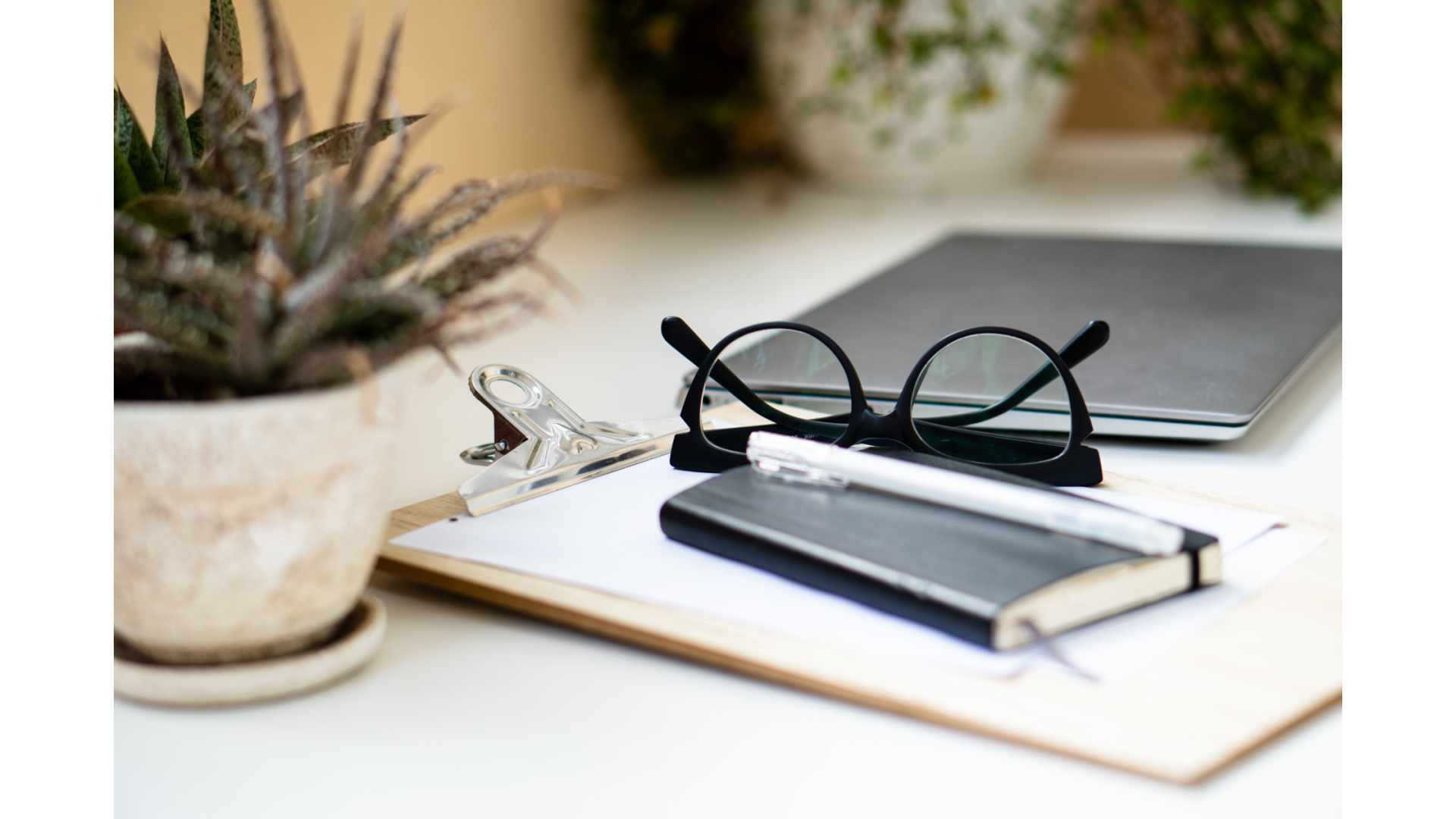 GK Marketing Online | A clipboard with a notebook , pen and glasses on it.