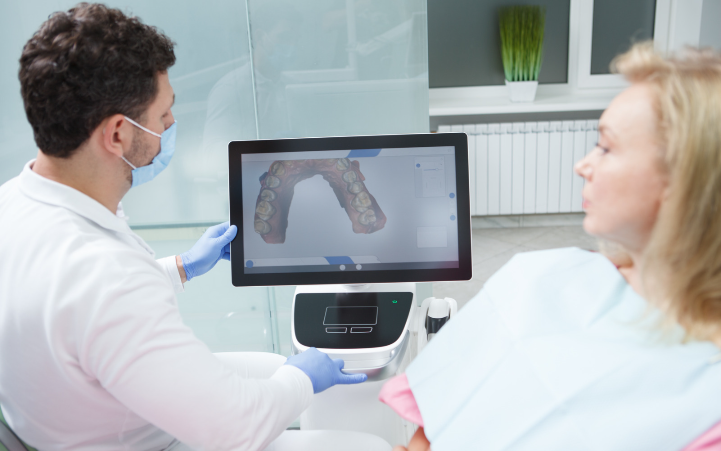 A dentist is showing a patient a picture of her teeth on a computer screen.