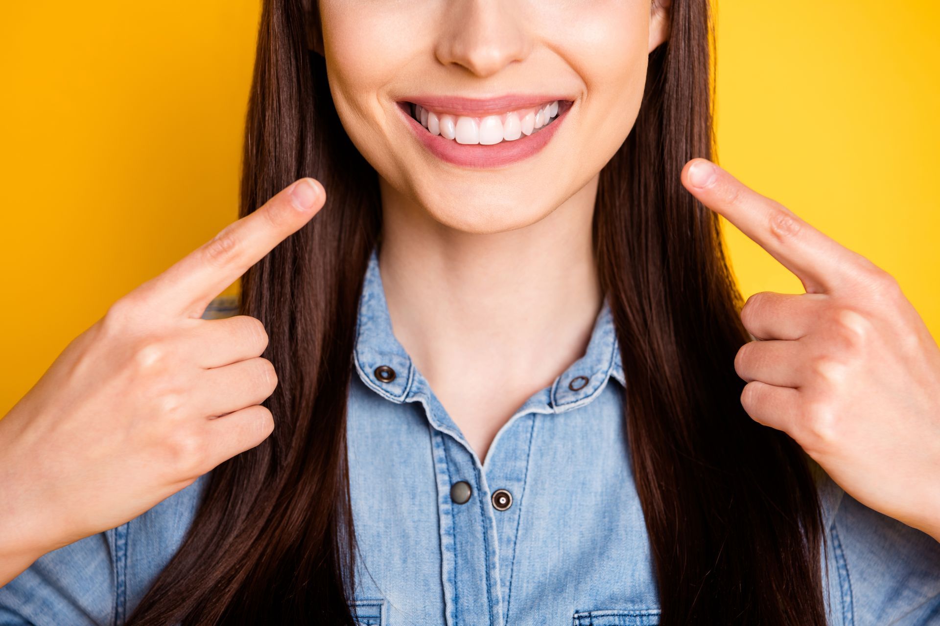 woman pointing to mouth smiling | Get teeth whitening from our cosmetic dentist in Oak Point TX 75068