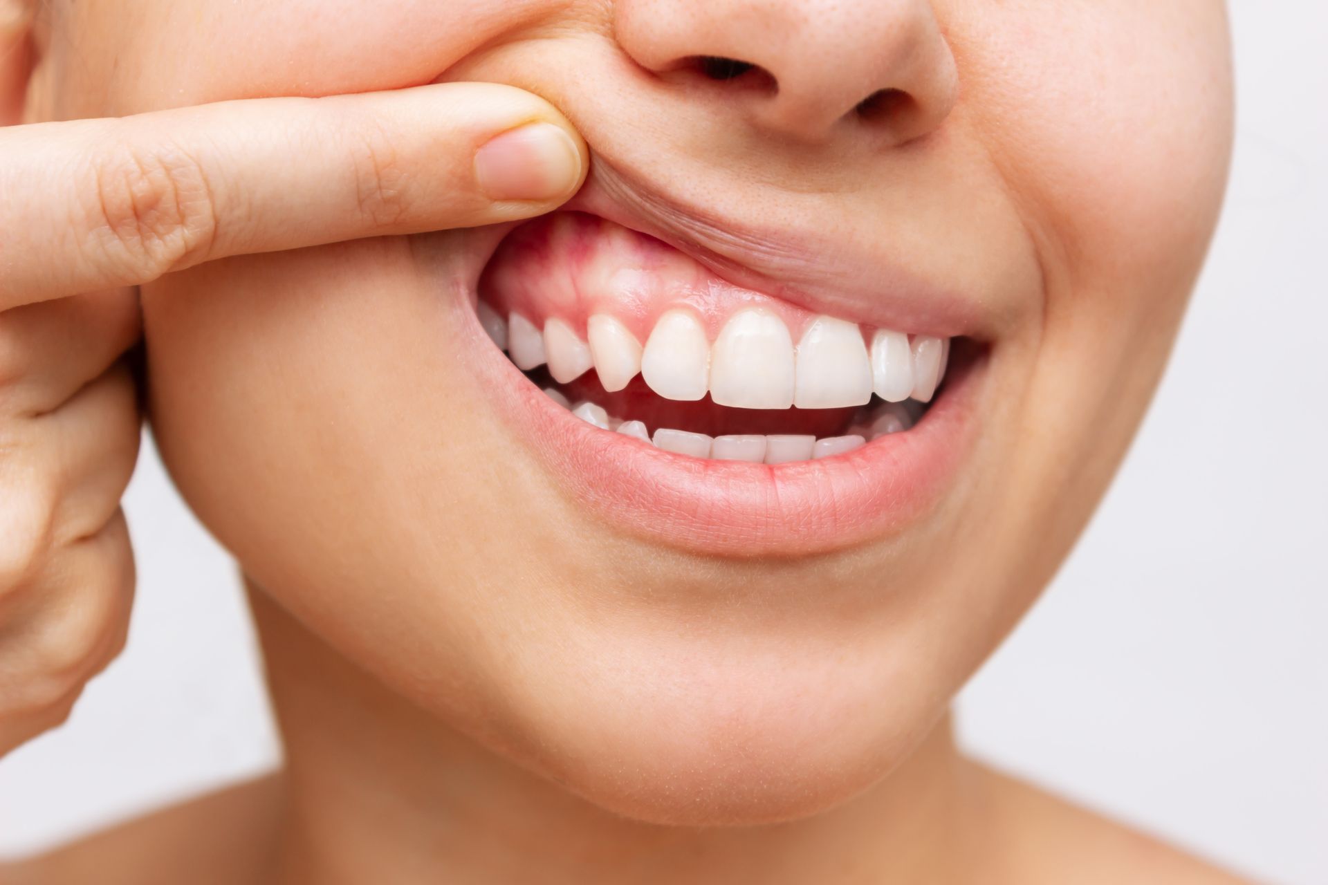 A woman is touching her teeth with her finger.