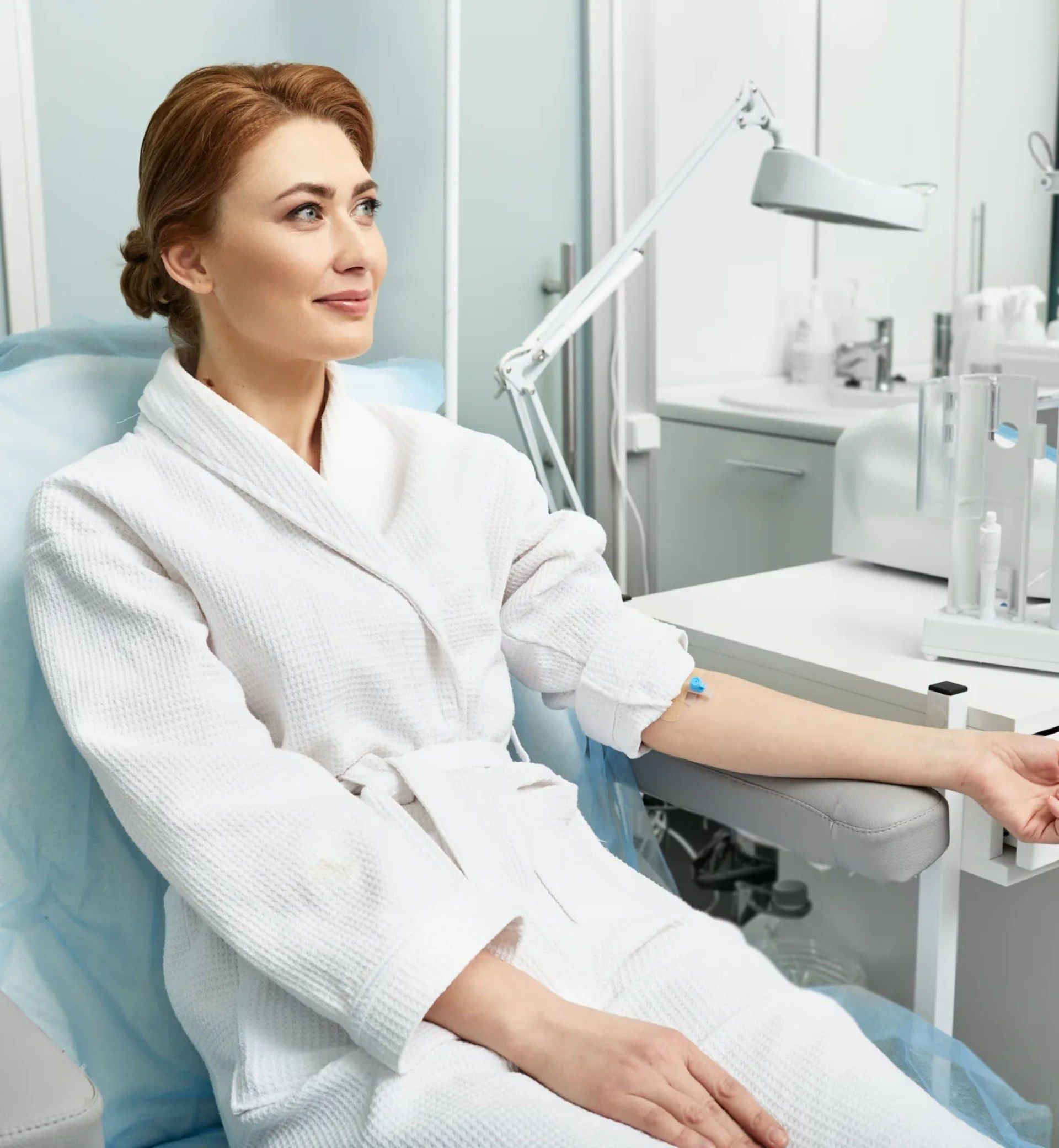 A woman in a bathrobe is sitting in a chair with a syringe in her arm.