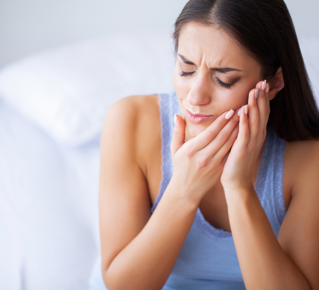 A woman is holding her face in pain because of a toothache.