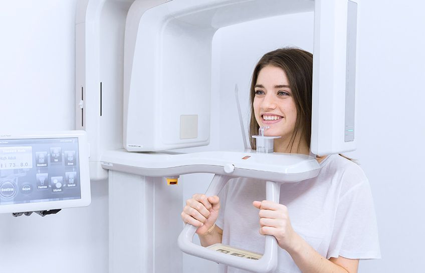A woman is getting an x-ray of her teeth in a dental office.