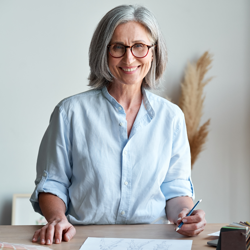 A woman is sitting at a desk with a pen in her hand.